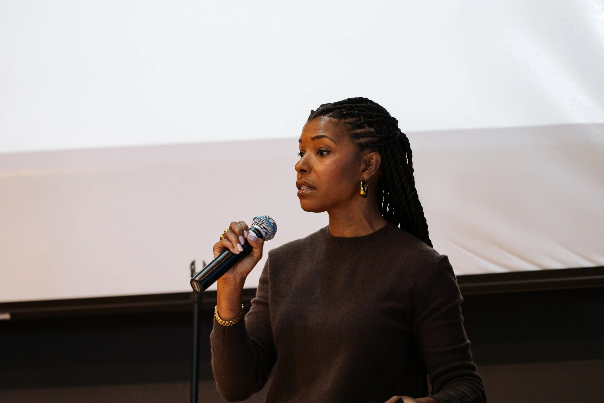 Dr. Kimberly McGlonn speaking on stage while holding a microphone during a keynote presentation