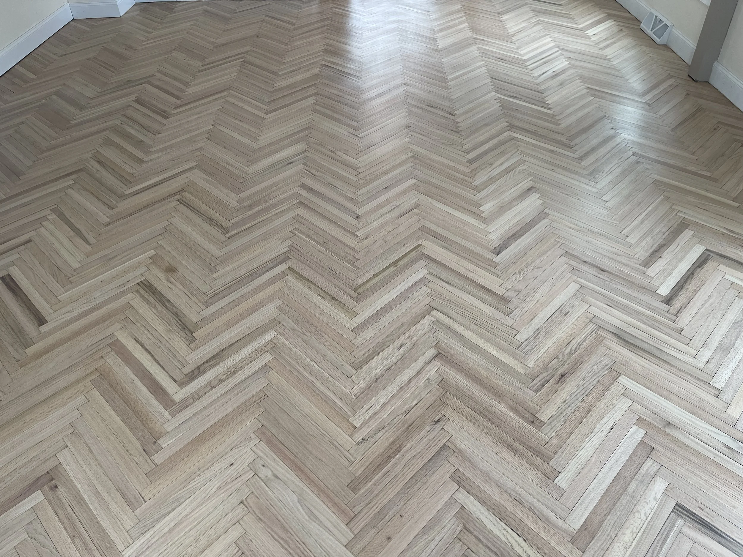 Herringbone pattern wood floor in a room.