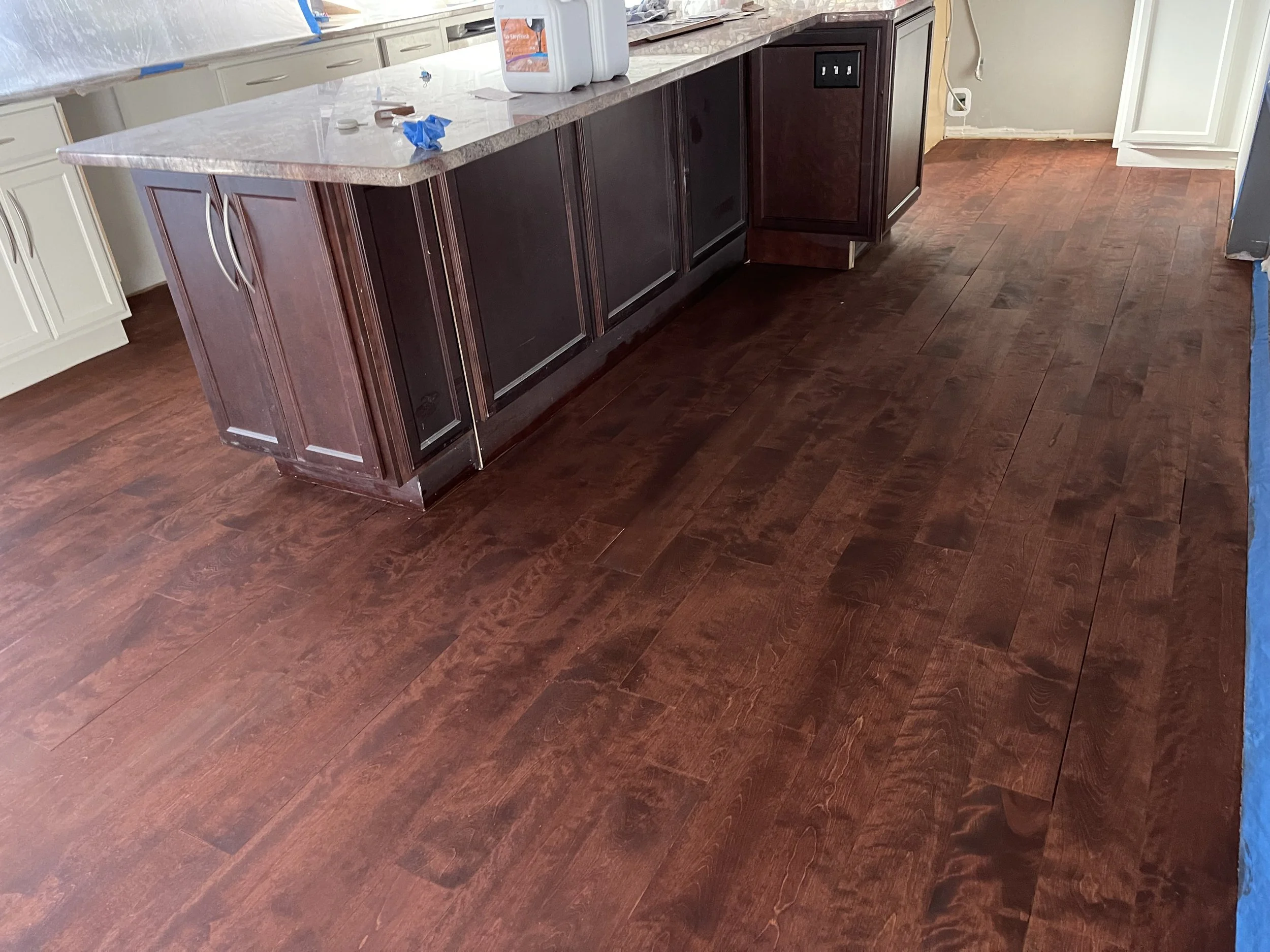 Kitchen with dark hardwood floors and an island with a granite countertop.
