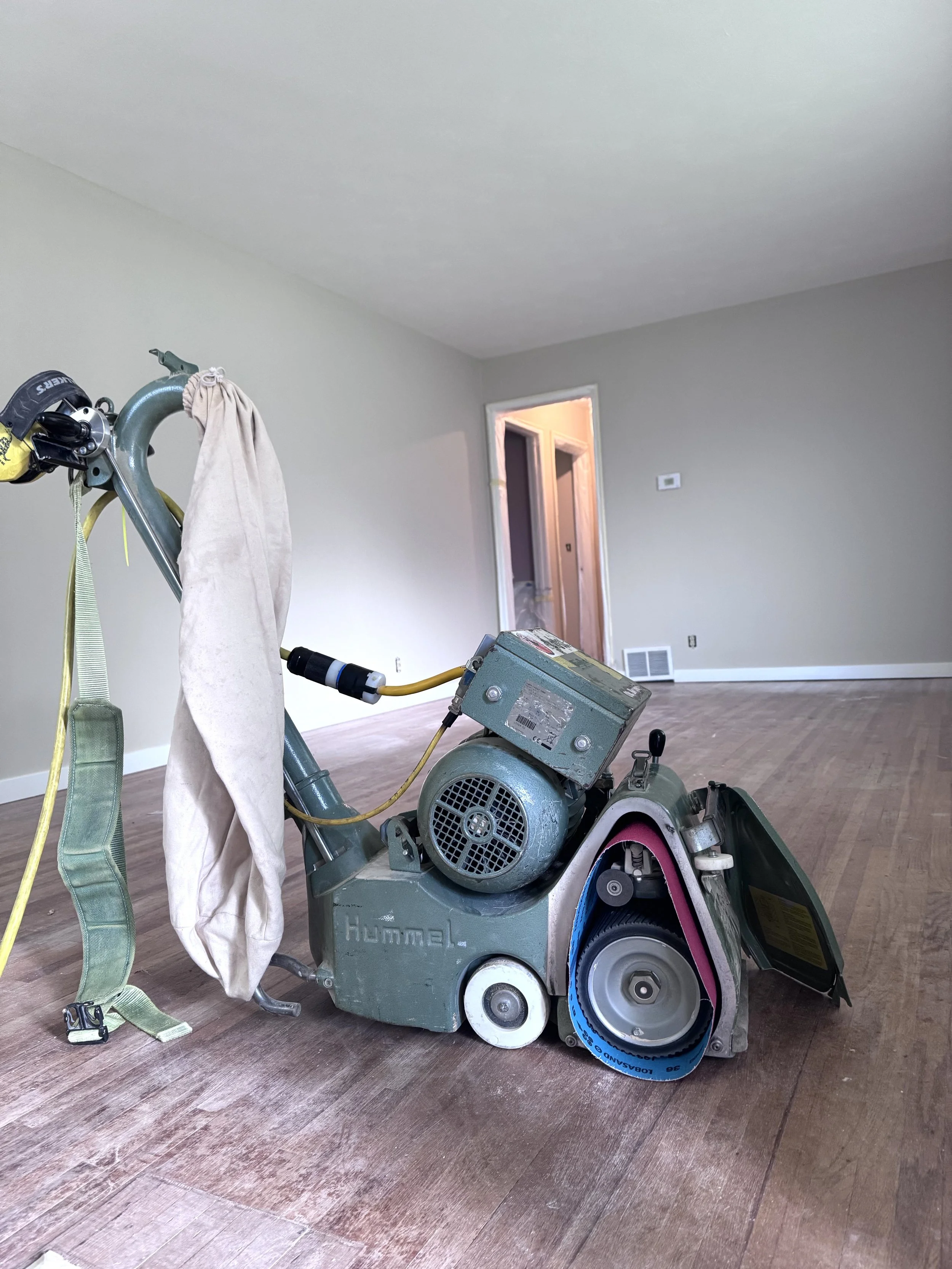floor drum sander being loaded with sanding belt before sanding wood floor