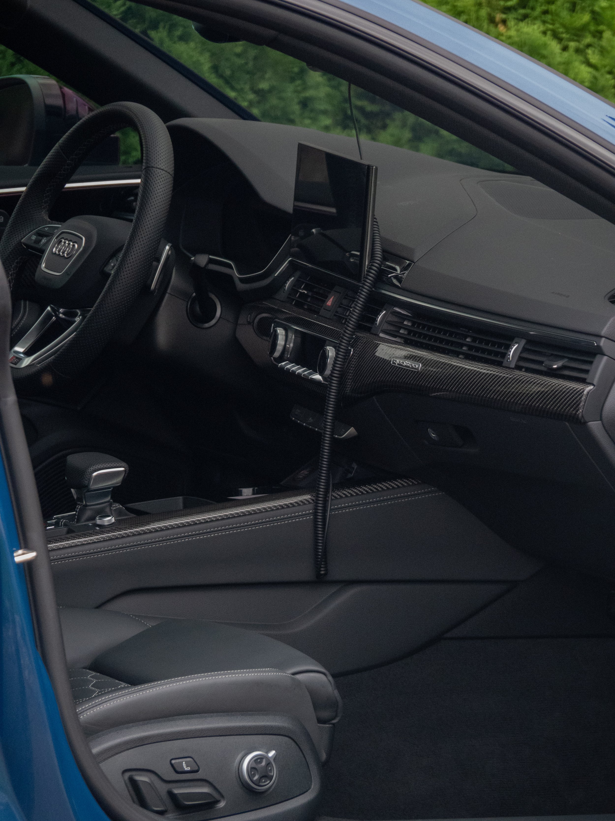Black interior of a modern luxury car with leather seats, steering wheel, dashboard, and multimedia display.