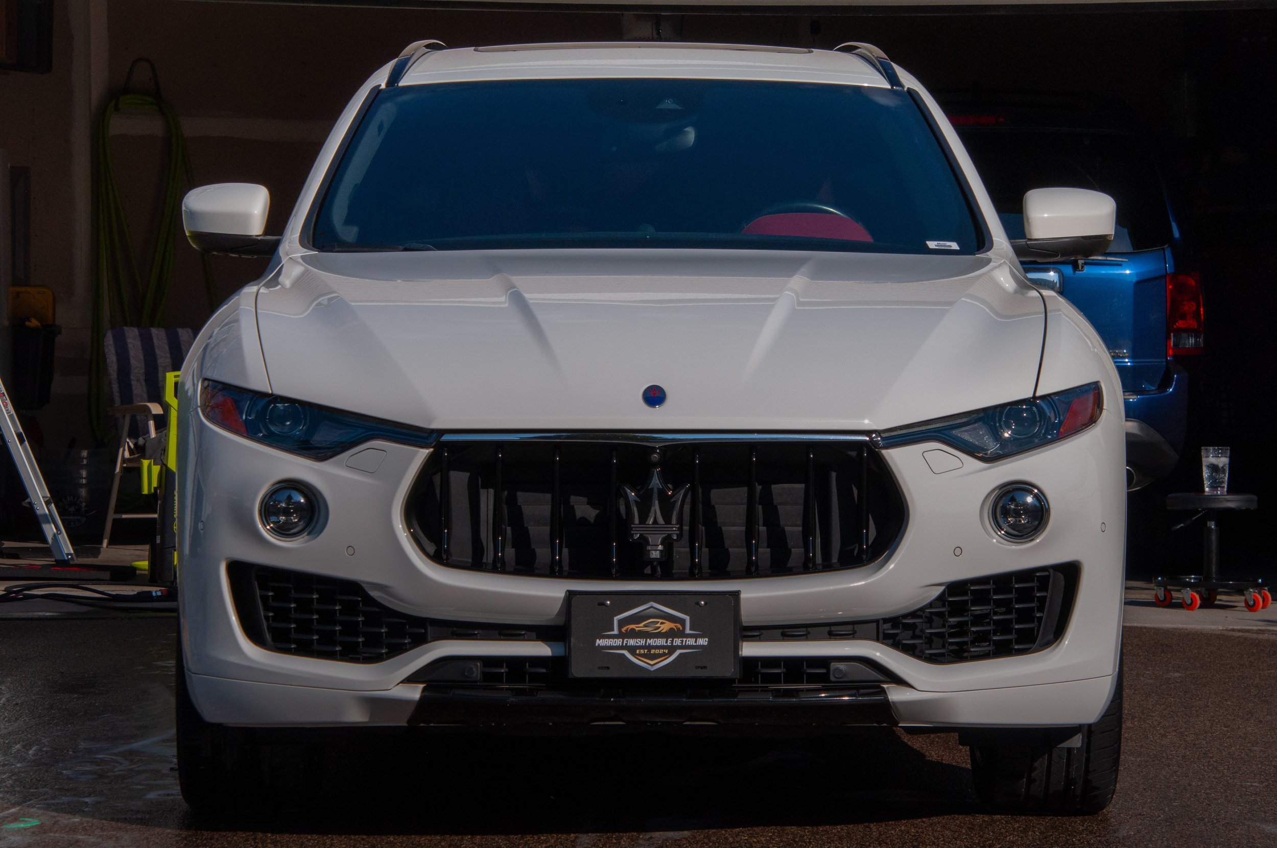 Front view of a white Maserati SUV in a garage.