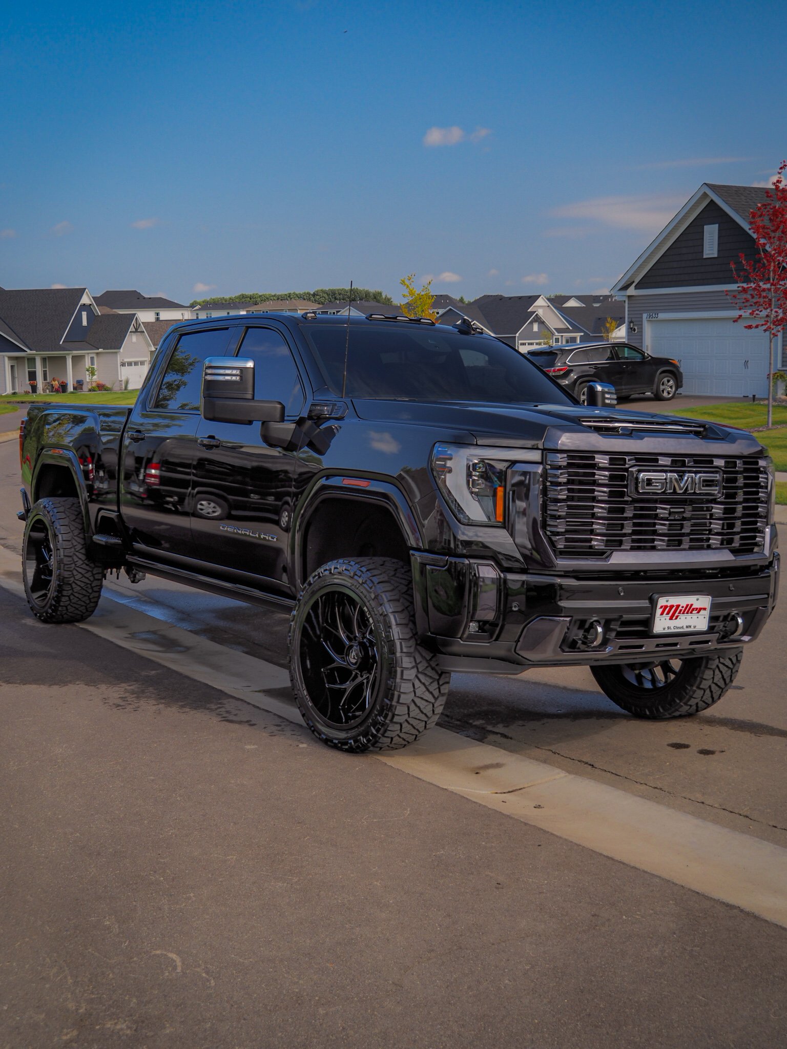 Black GMC truck parked on residential street with houses in background.