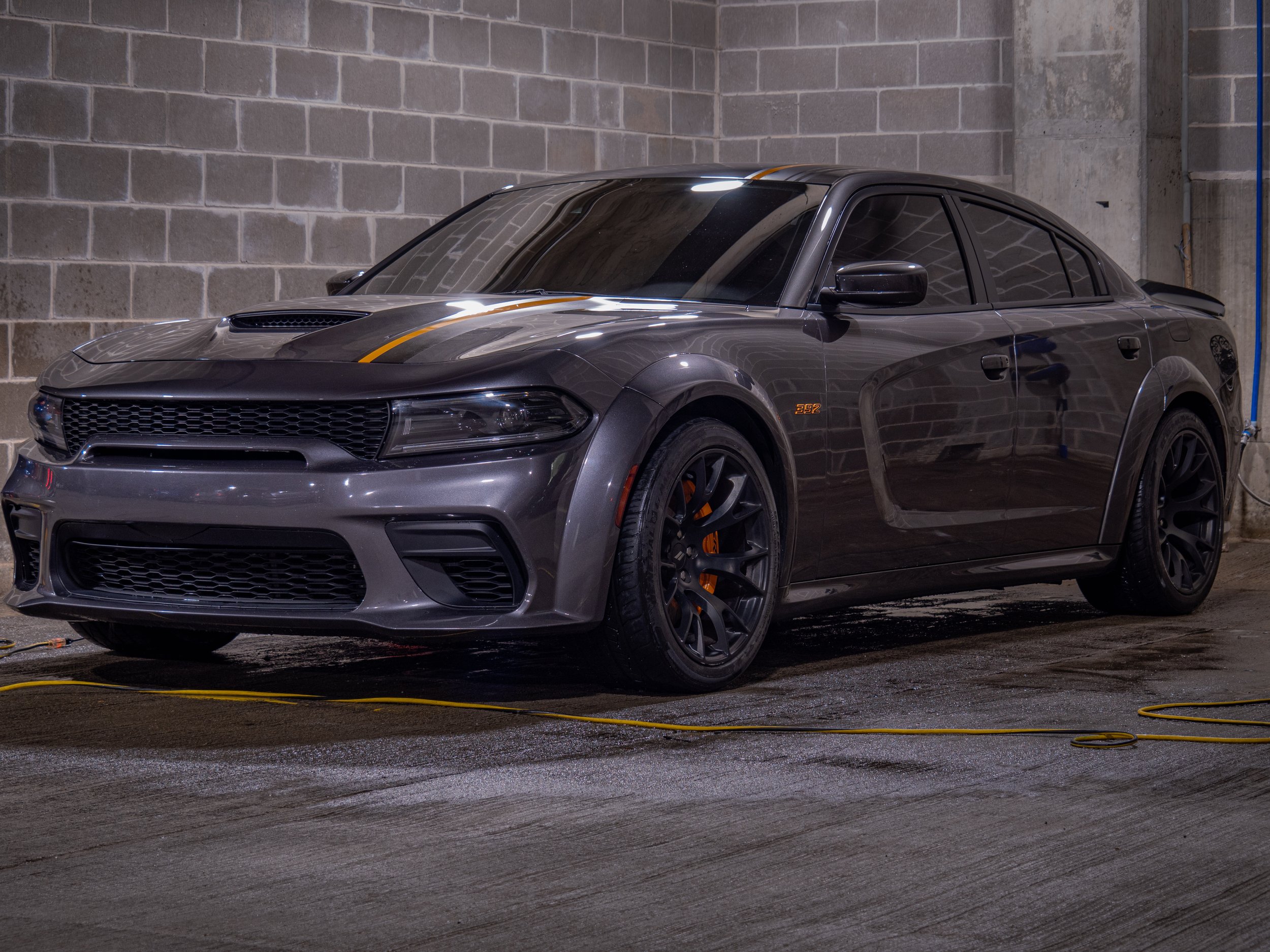 Gray sports car parked indoors, surrounded by concrete walls.