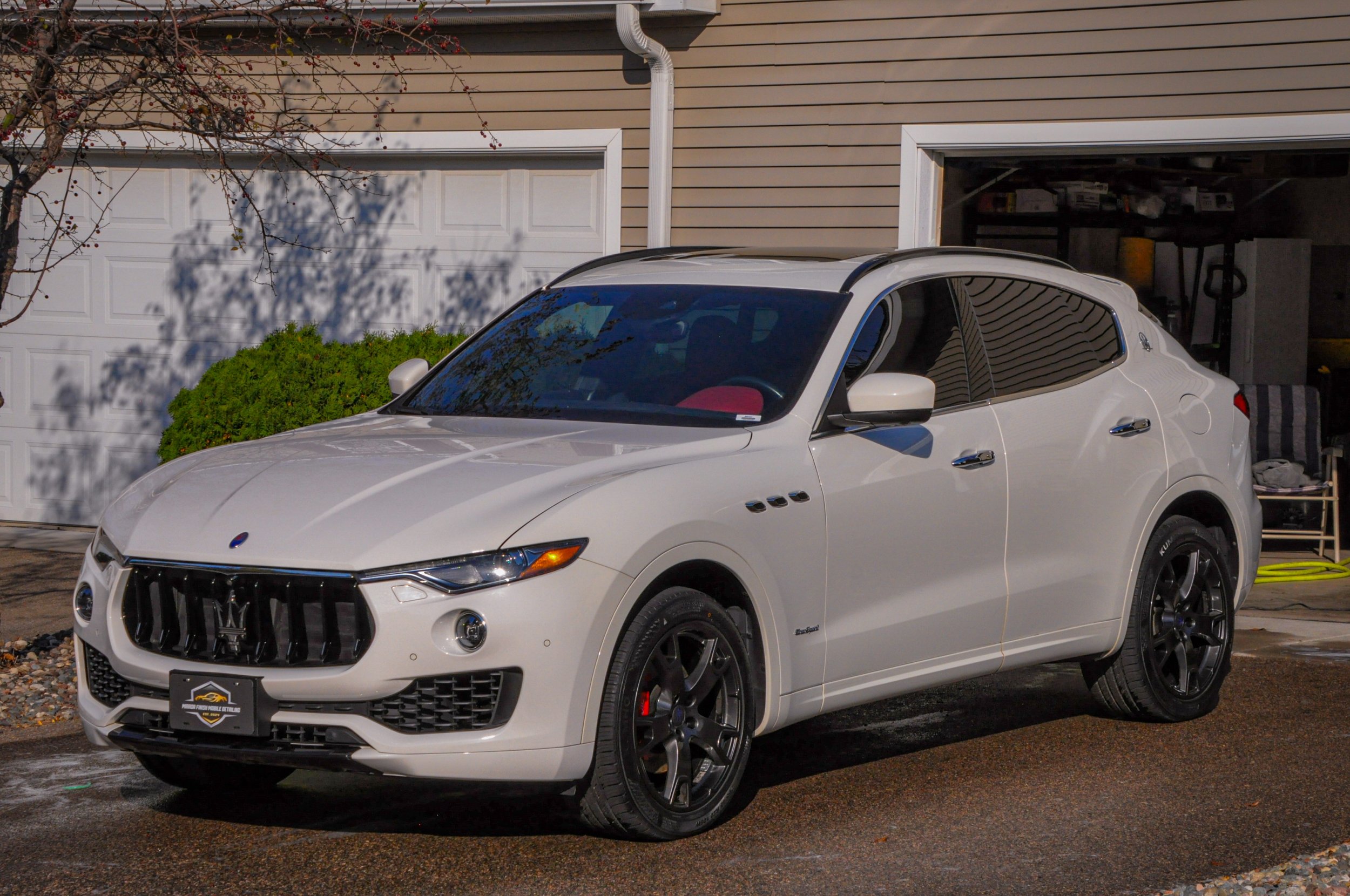 White Maserati Levante parked in front of a garage