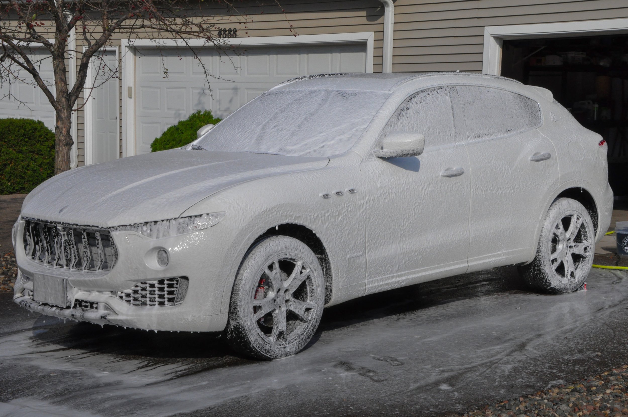 Car covered in white foam for washing in driveway
