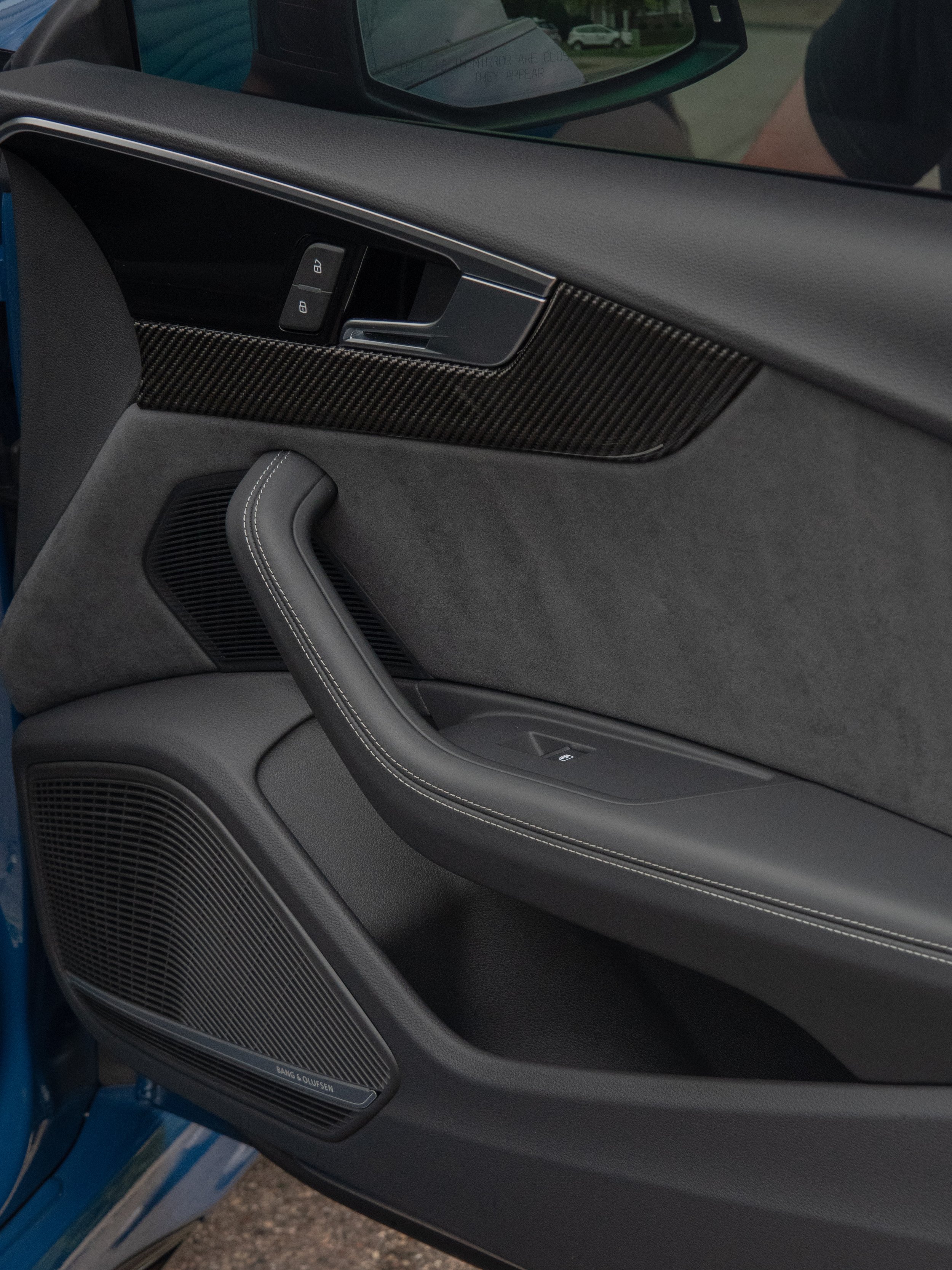 Car interior door panel with carbon fiber trim and integrated speaker