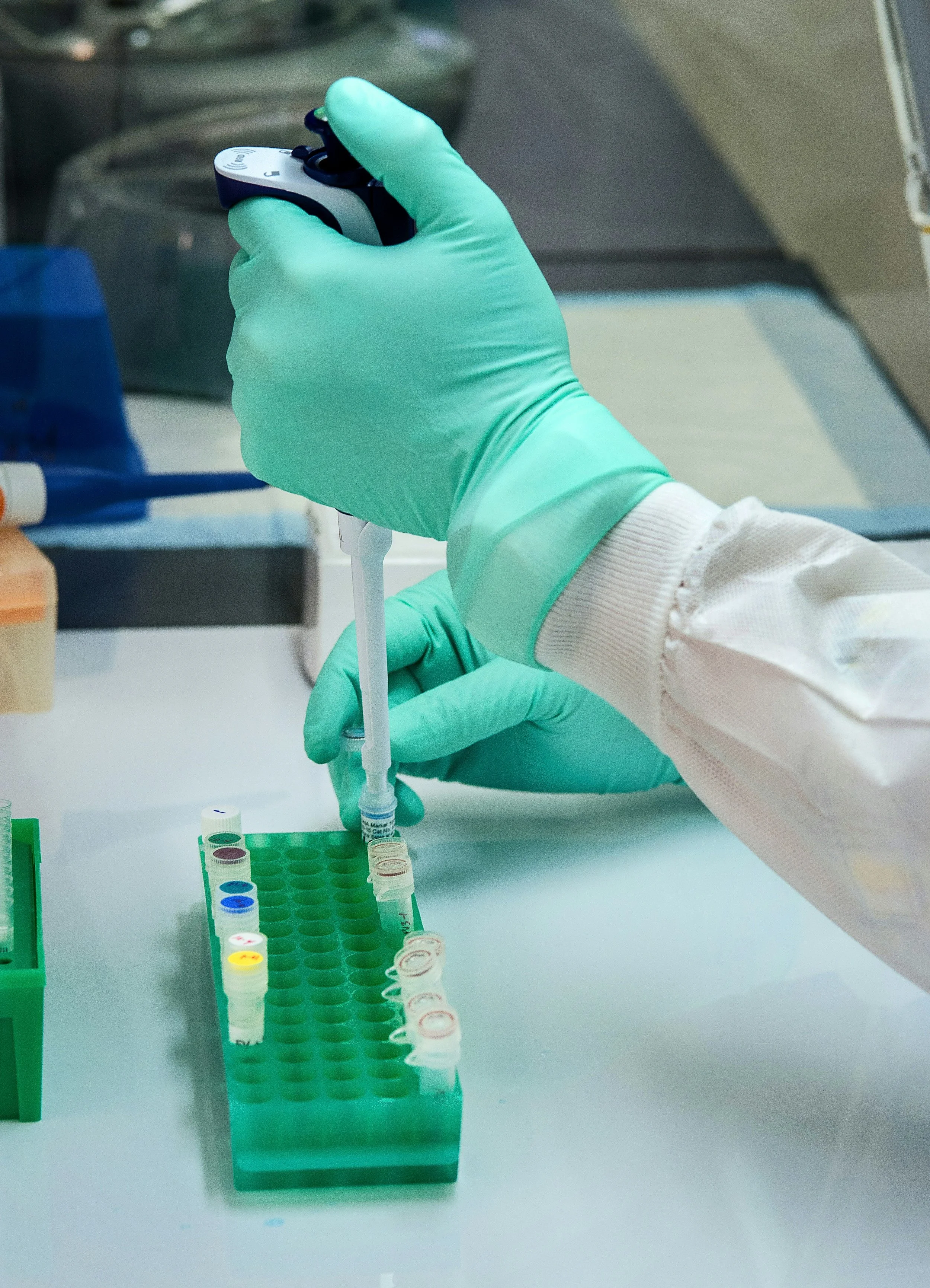 Person using a pipette to drop liquid into containers