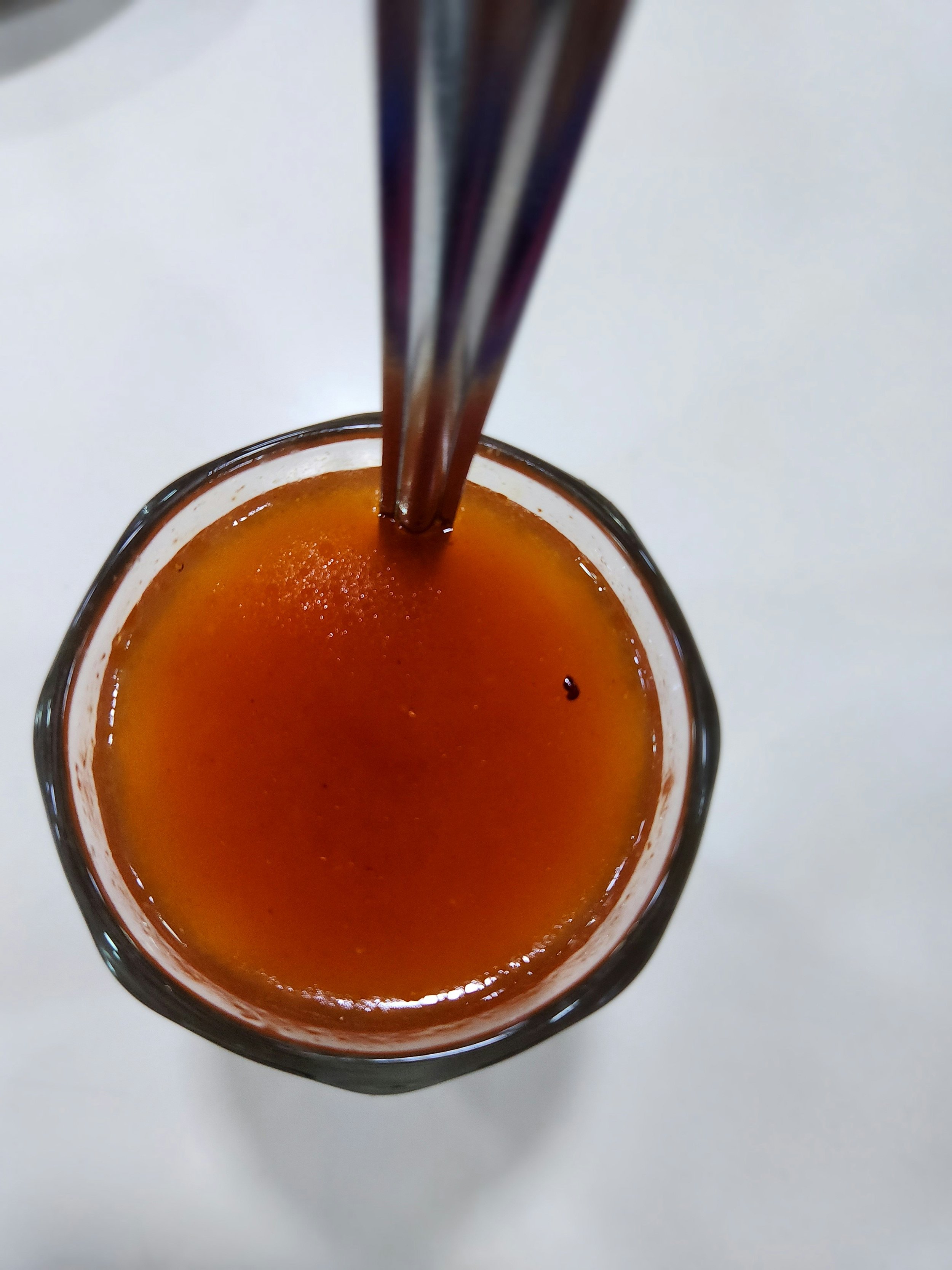A beaker containing a viscous liquid with a straw coming out