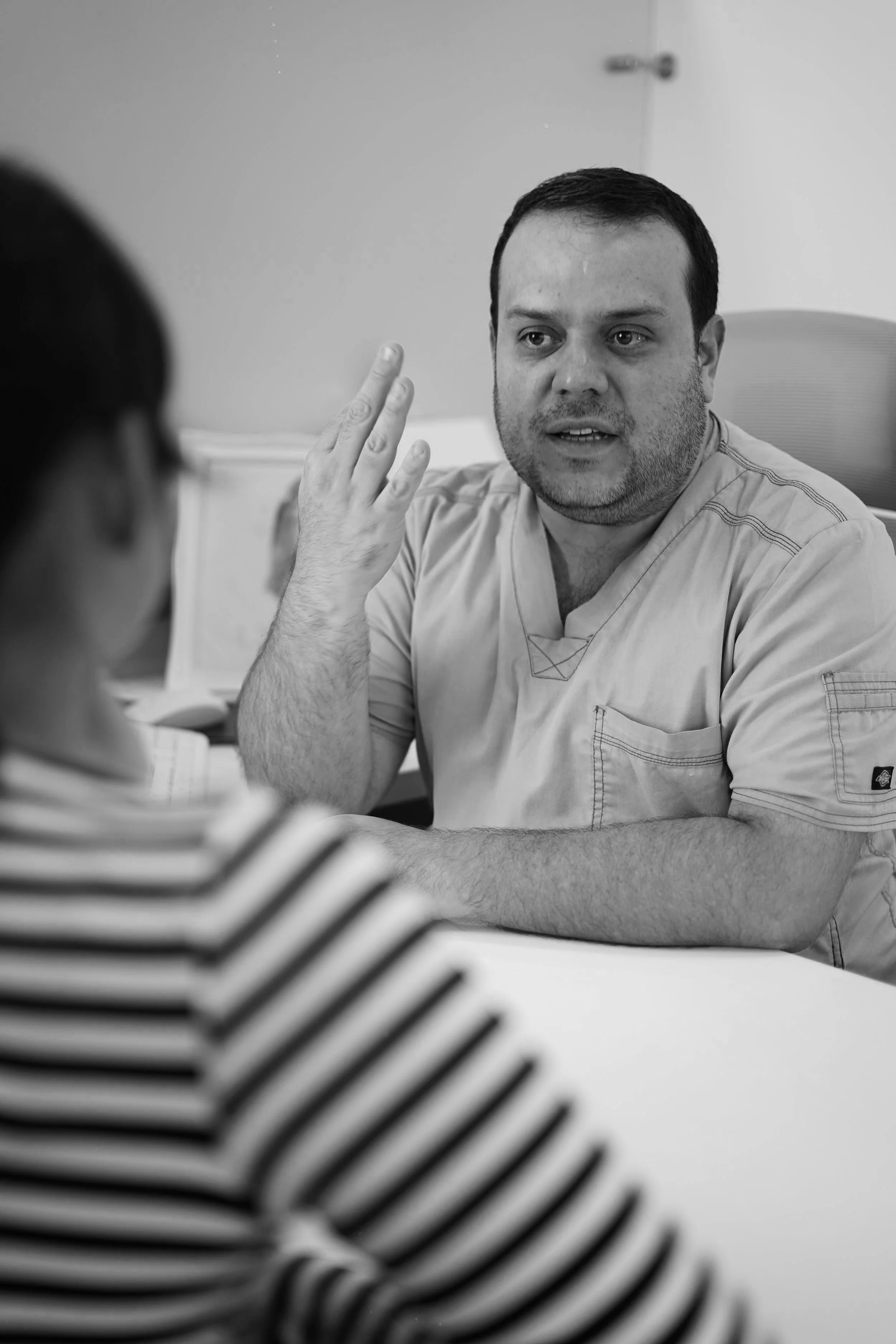 Un médico hablando con una paciente en una consulta médica, en blanco y negro.