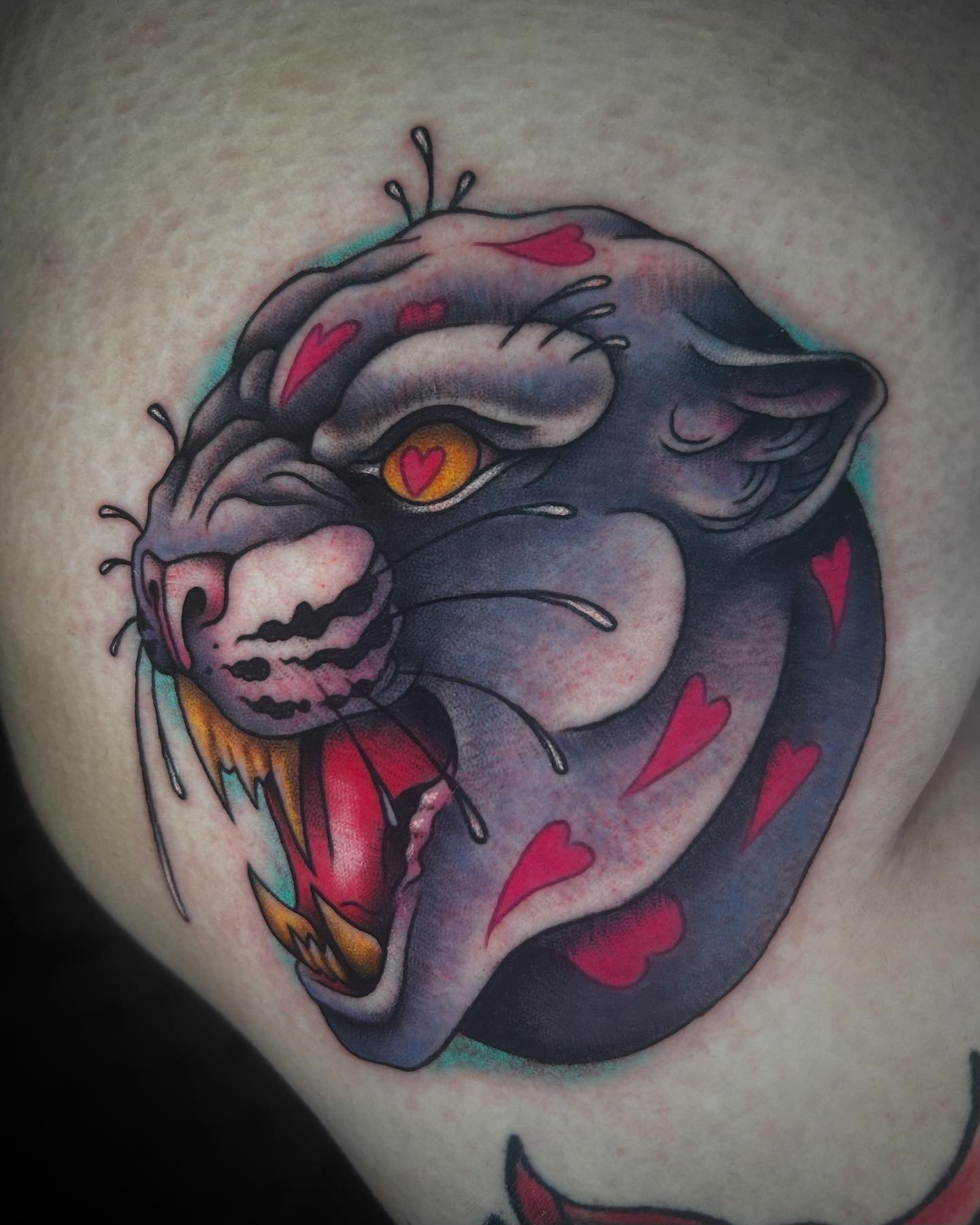 Colorful tattoo of a female face with eyes closed, surrounded by red hearts, with dark hair and makeup, on skin.