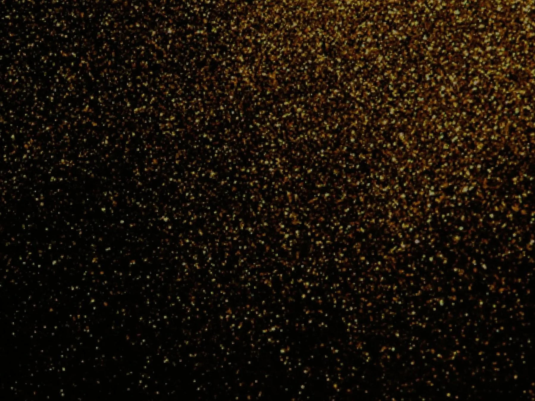Close-up of a black surface with glittering gold particles.