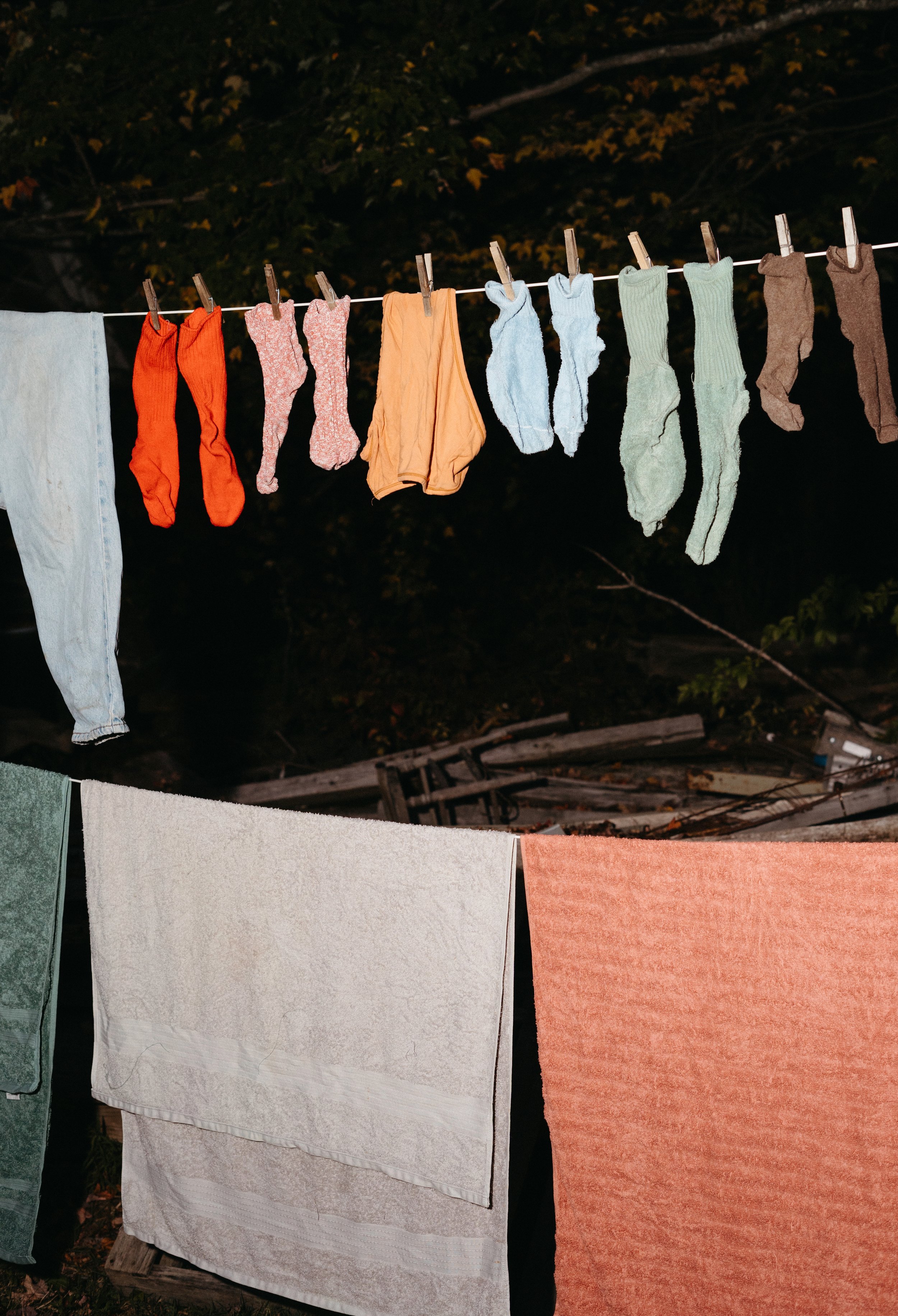 Clothes and towels hanging on a clothesline, drying outdoors at night.