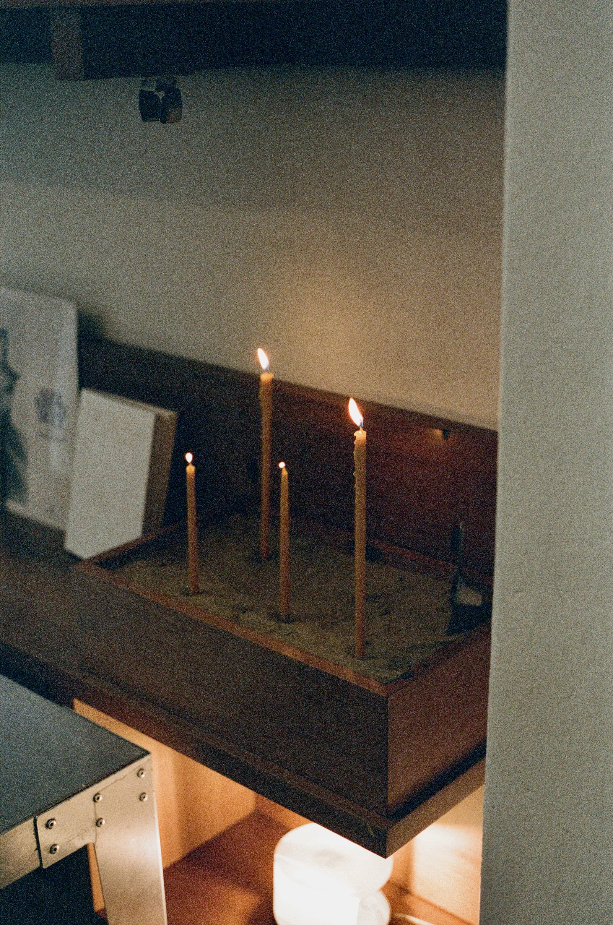 Four lit candles in a wooden box.