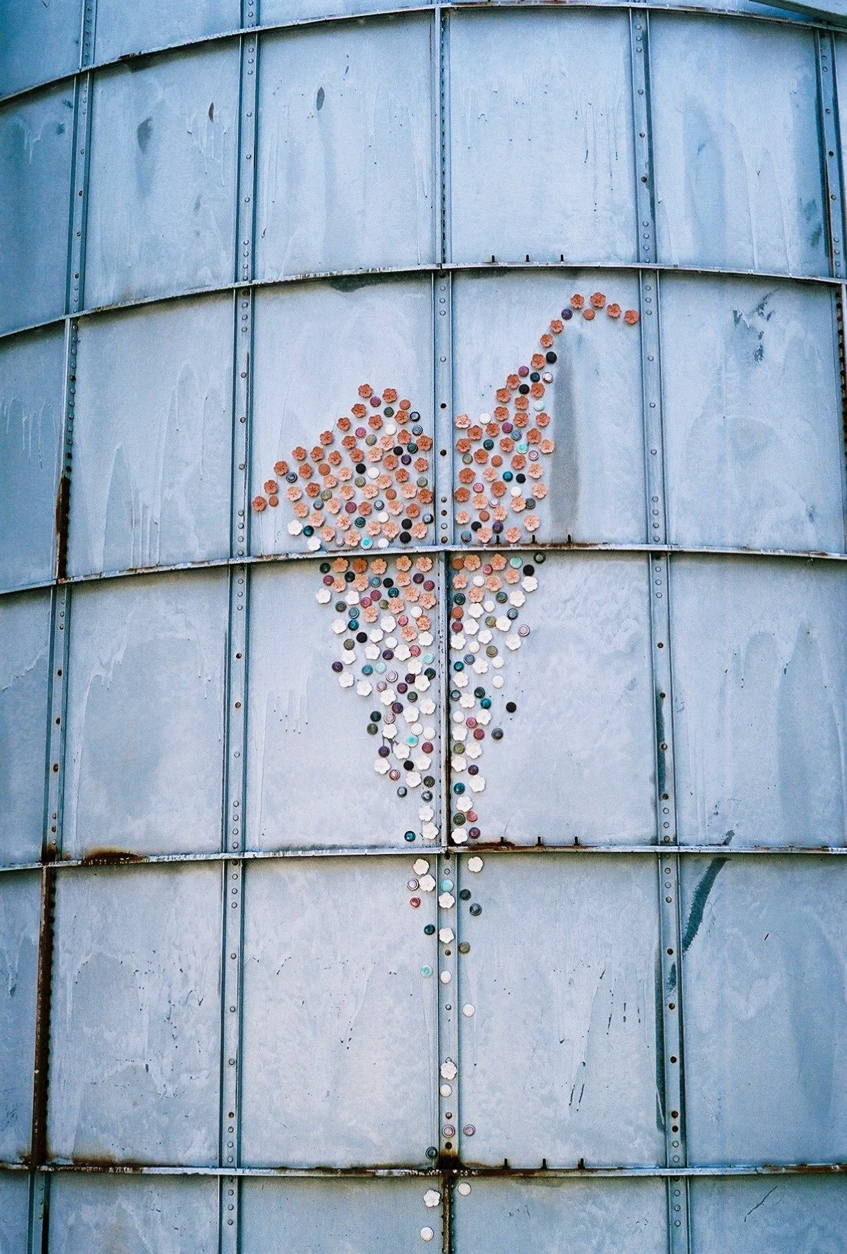 A large metal surface with a depiction of a whale created from colored bottle caps.