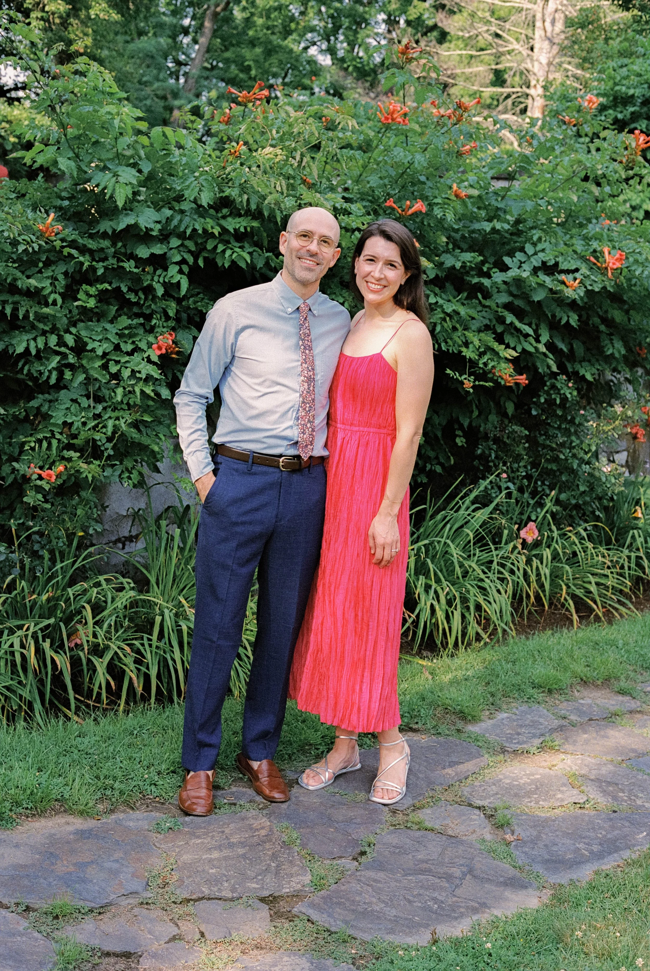 A color film photograph of a couple of wedding guests, dressed colorfully and smiling at Troutbeck in Amenia, New York
