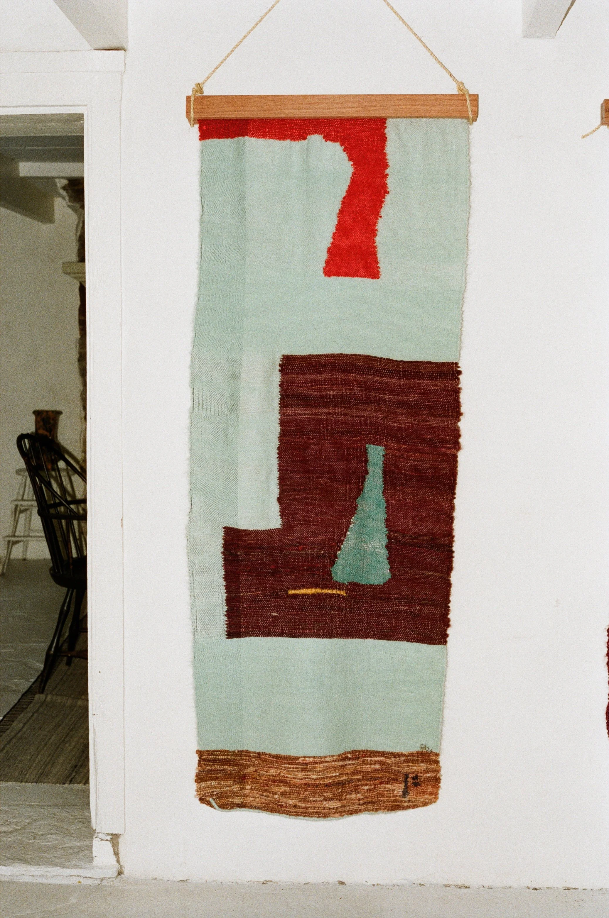 Wall hanging tapestry with abstract geometric patterns in red, brown, and light blue.