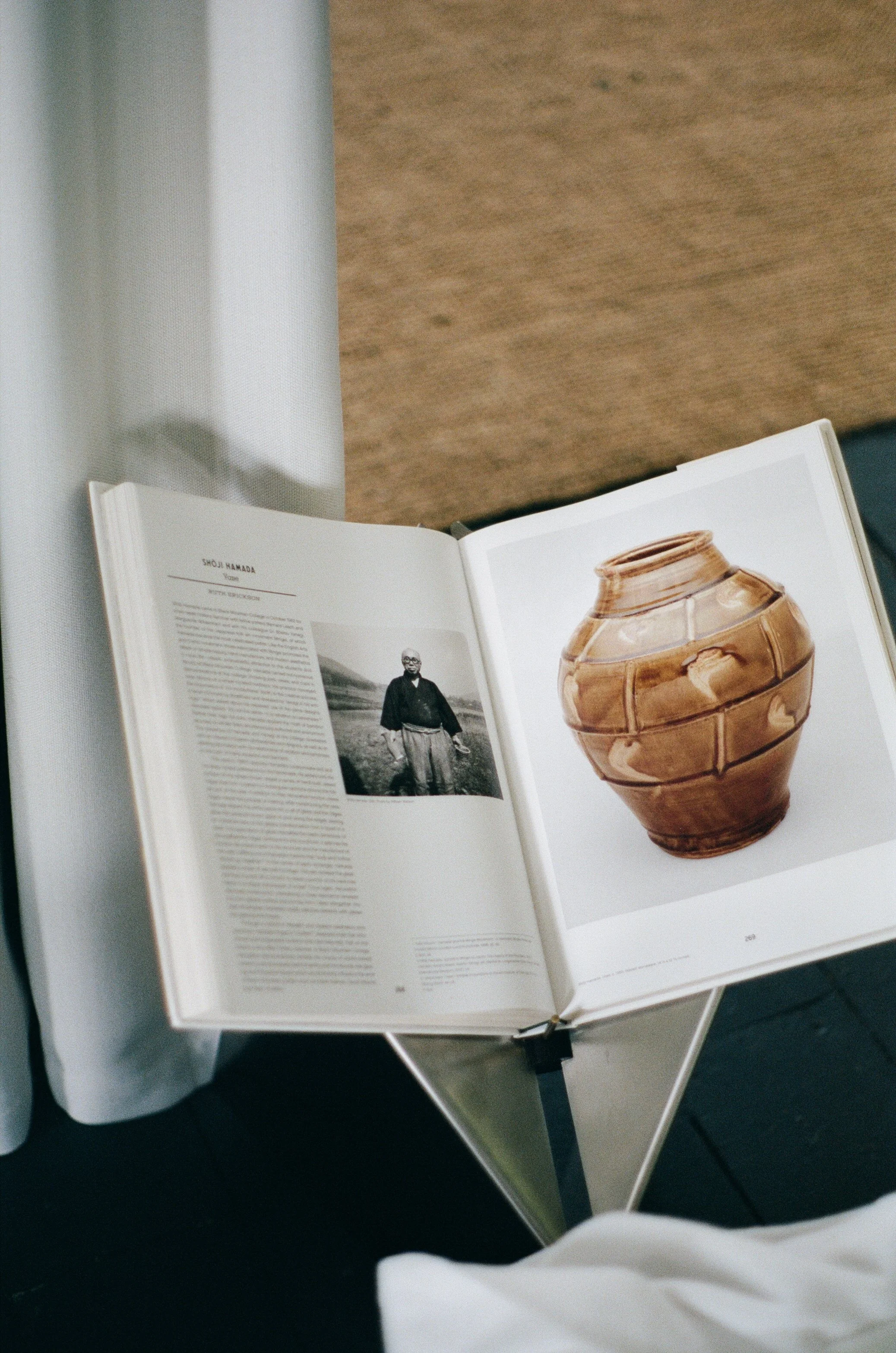 Open book displaying a black and white photograph of a man and a picture of a ceramic vase.
