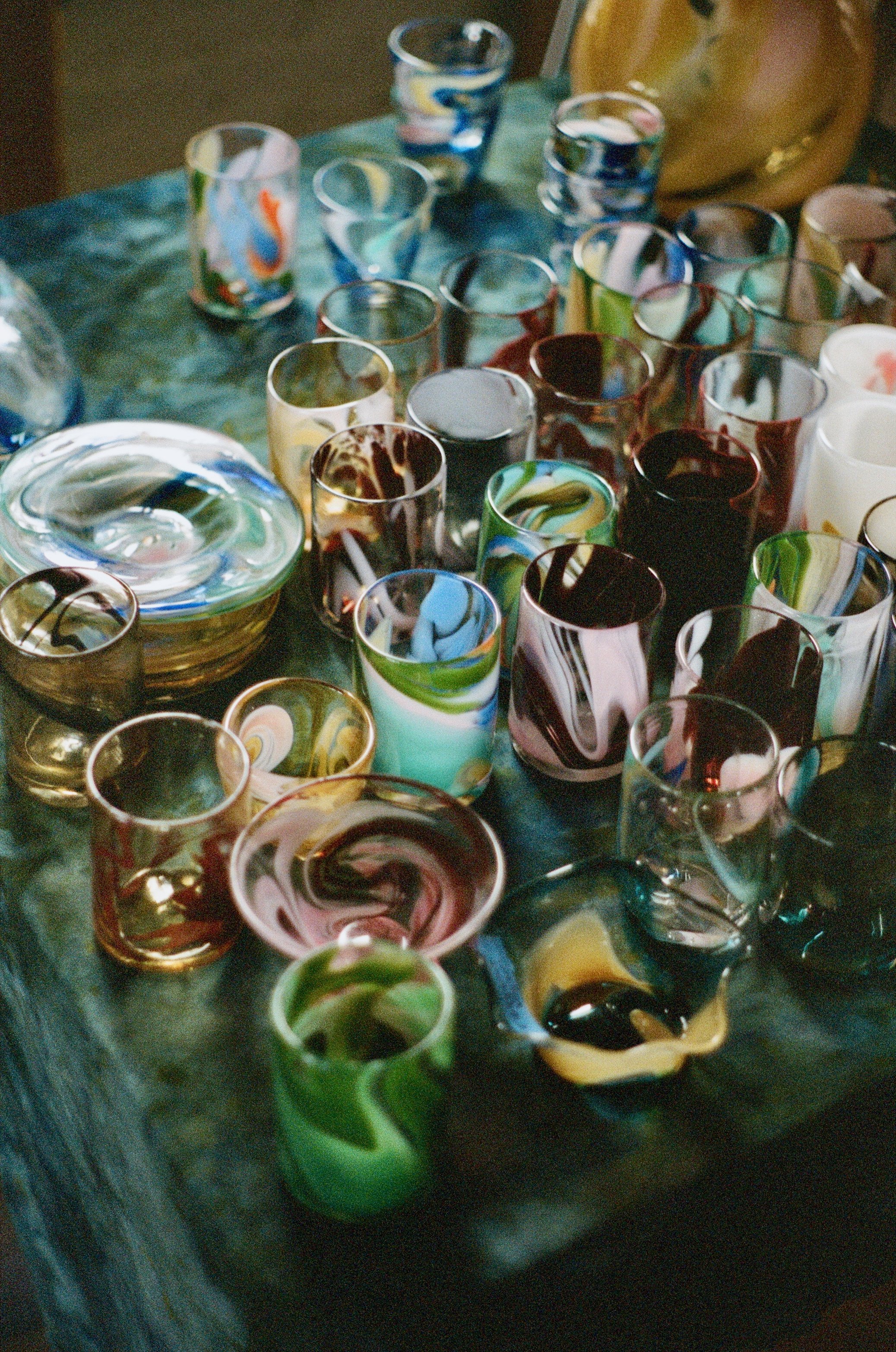 Colorful glassware glasses with various marbled patterns on a dark wooden table.