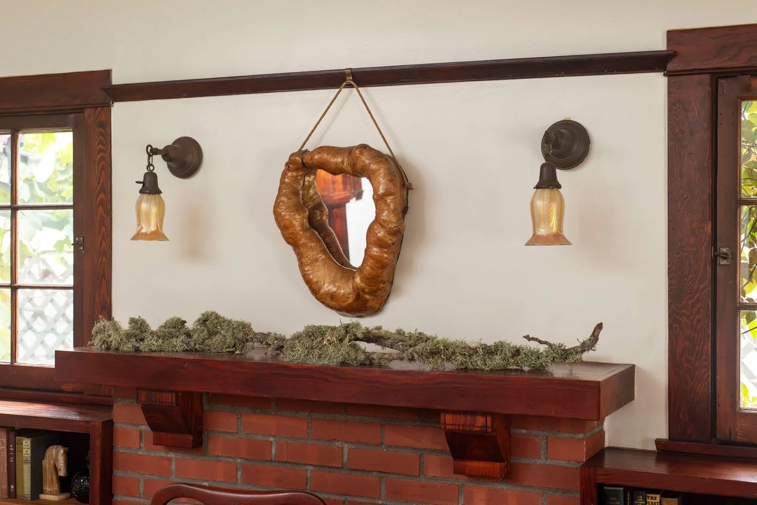 Photo by: Steven Dewall
A vintage burl root mirror shaped like the hollow of a tree hangs above the fireplace, complimented by a collection of beautiful moss-covered branches that rest on the mantel.