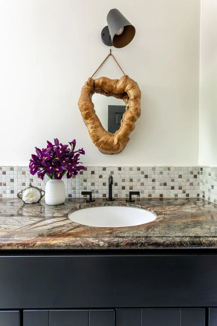 Photo by: Ace Misiunas
A mid-century-inspired wall sconce sits above a vintage burl root mirror shaped like the hollow of a tree.