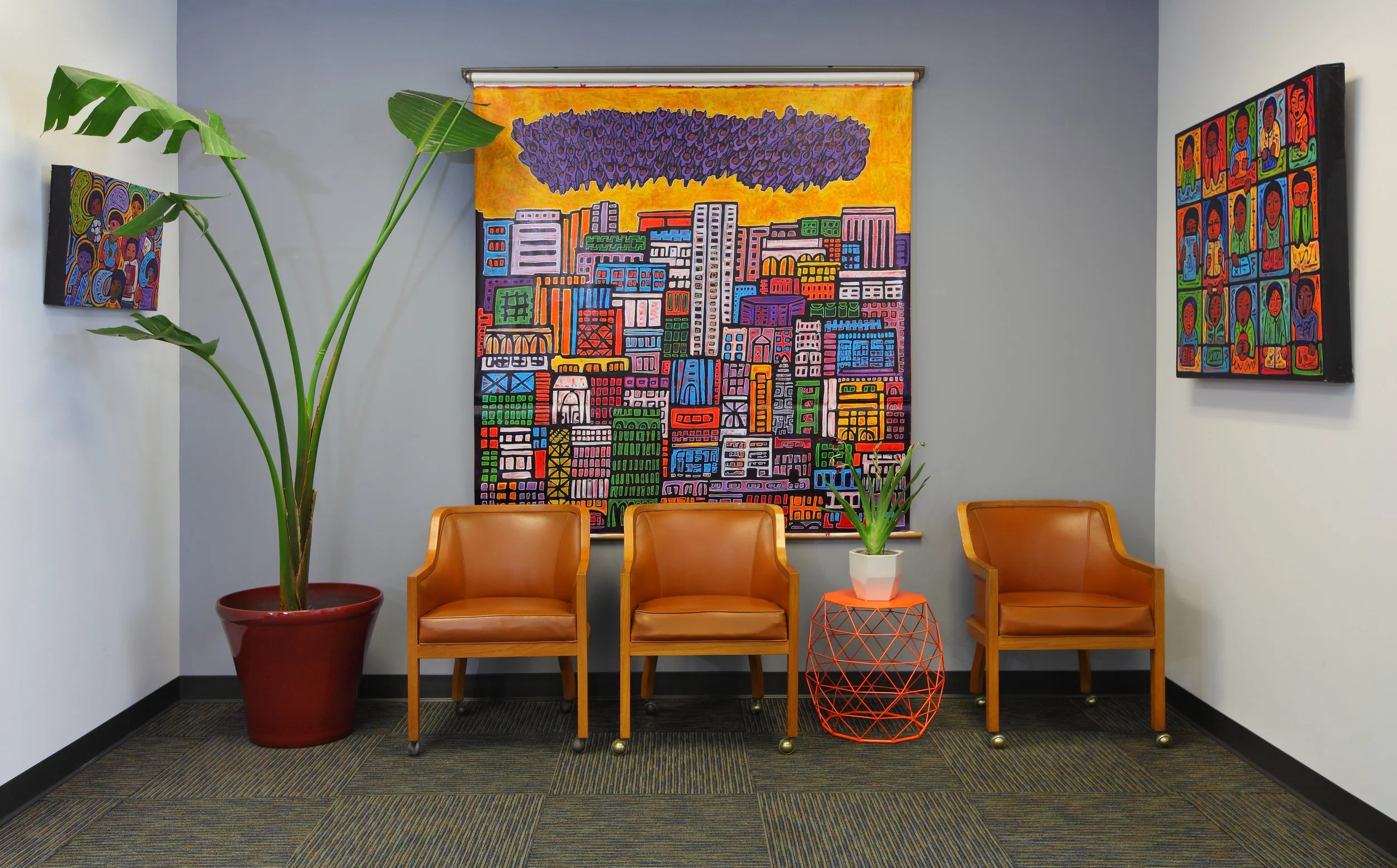 Photo by: Chas Metivier
Recycled carpet tiles and vintage oak chairs exhibit fashionable, functional sustainability.  Paintings Exodus, Escuela, and Nabe are by Jose Ramirez.