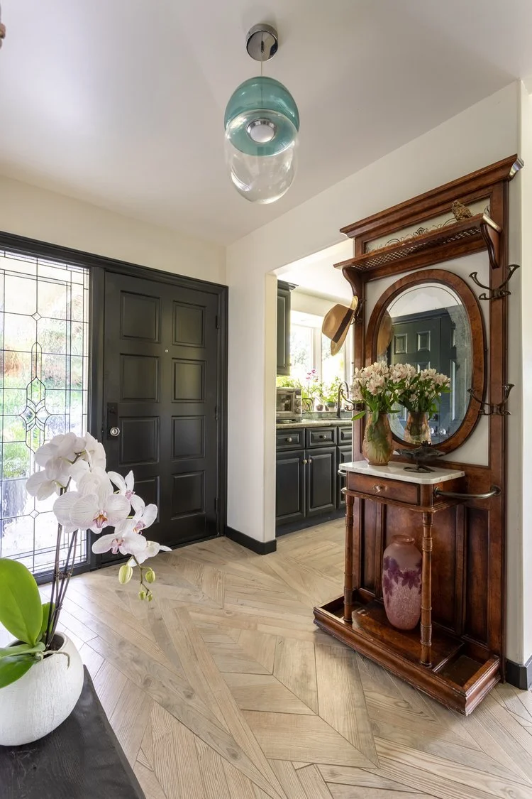 Photo by: Ace Misiunas
An Italian-designed hand-blown pendant light creates soft lighting in this entry to the home, while a vintage hall tree features a collection of nature-inspired objects. The trim throughout the home's public rooms is painted th