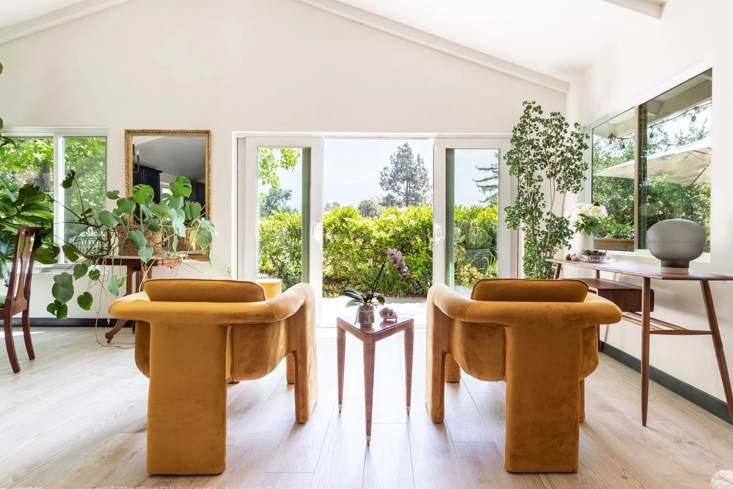 Photo by: Ace Misiunas
A pair of contemporary marigold yellow armchairs with custom arch-shaped ottomans create an area of warmth that brings out the earthy-toned highlights throughout the room. A German-designed, hand-blown, smokey taupe glass table