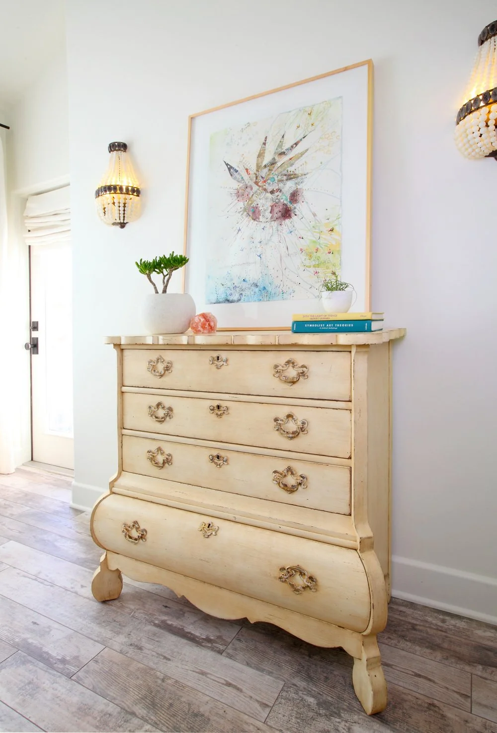 Photo by: Chas Metivier
Artwork by Karrie Ross is flanked by delicate beaded sconces and natural linen roman shades.