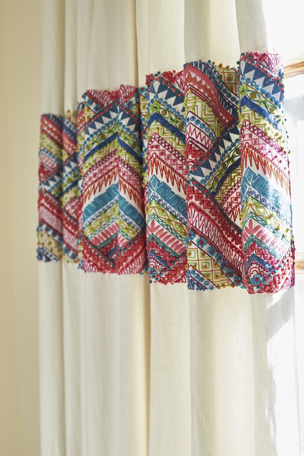 Photo by: Steven Dewall
Handmade draperies are banded with colorful embroidery in shades of fuchsia, teal, chartreuse and gold. 
