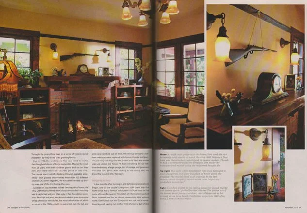 A cozy living room with a fireplace, bookshelves, and armchairs, decorated with vintage-style wall lamps and a mounted rifle, with a large window providing natural light.