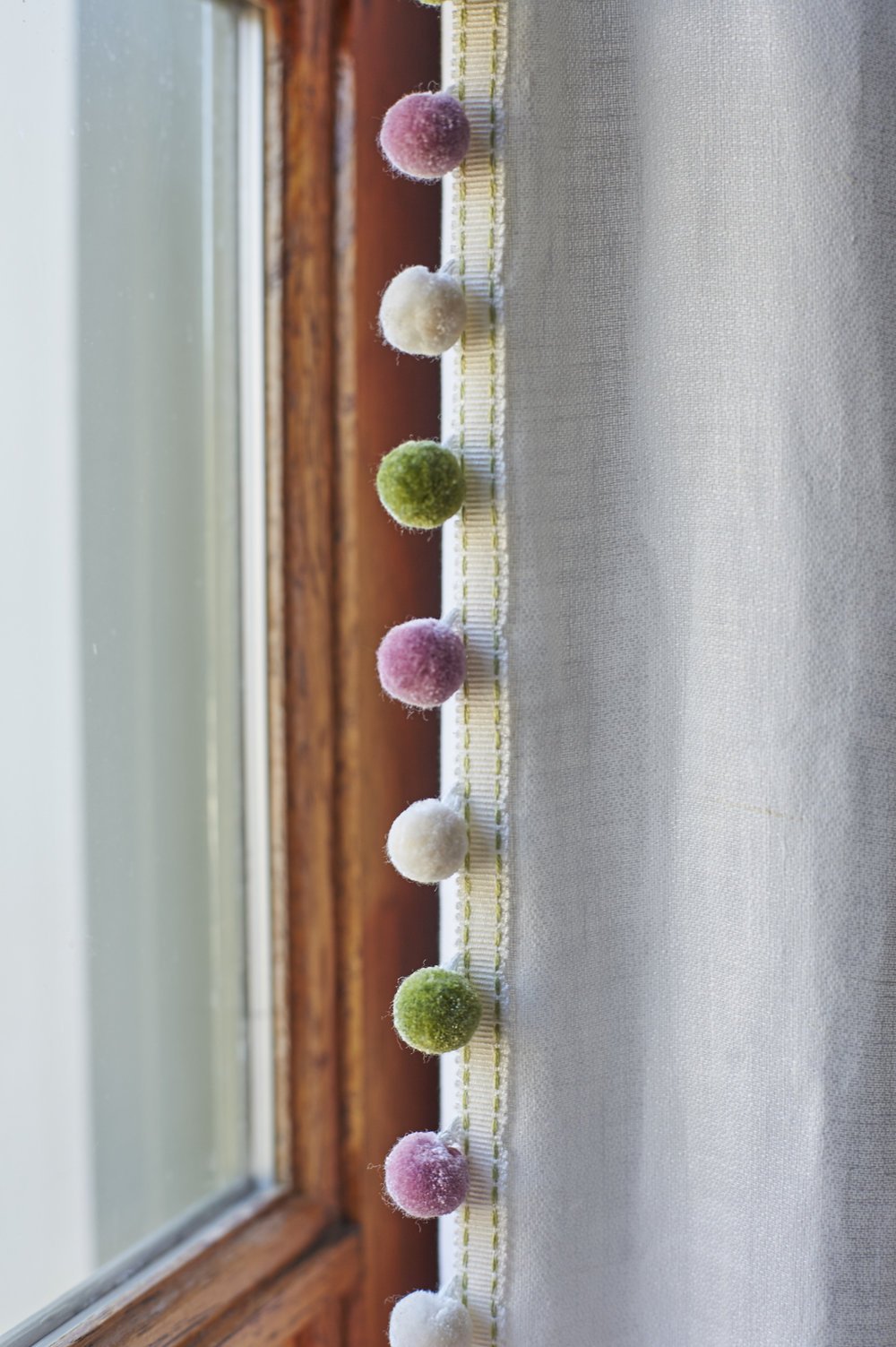 Photo by: Steven Dewall
Delicate pom-pom fringe in pink, green and white trims the edge of the custom drapery. 