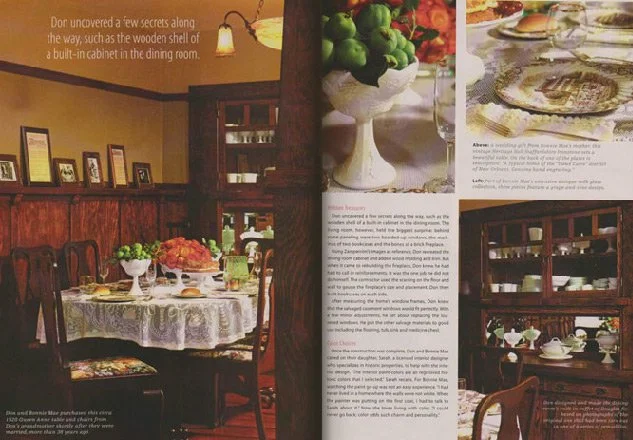 Photo of a cozy dining room with a round table covered with a lace tablecloth, set for a meal with white plates, glasses, and a bouquet of flowers in a vase.