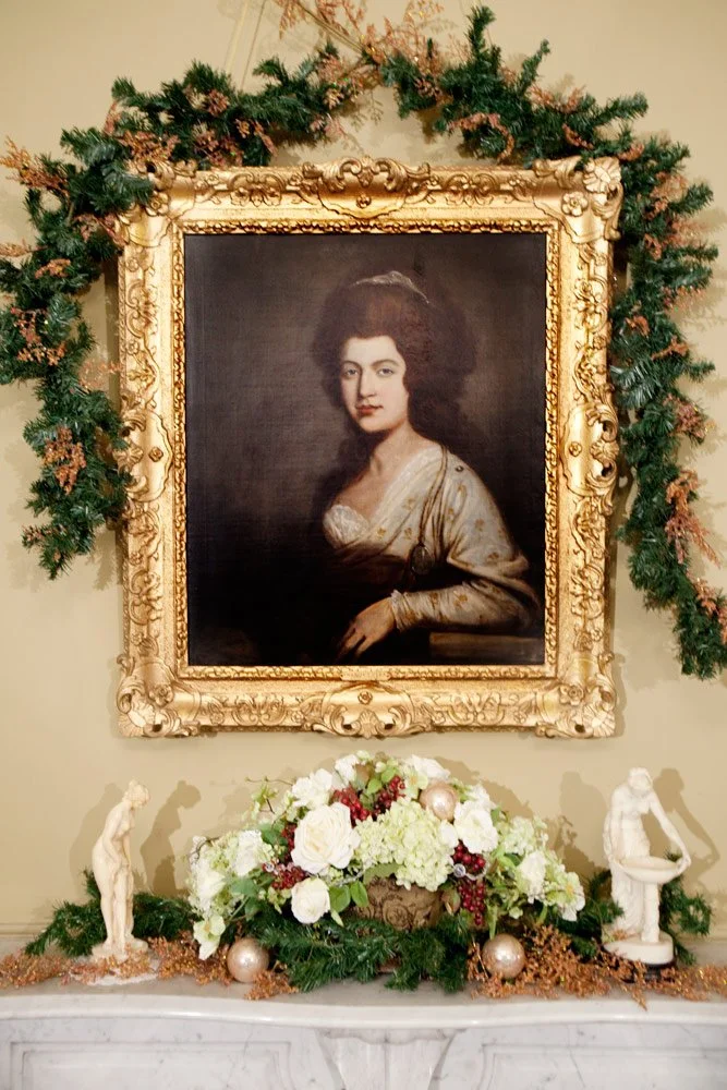 Photo by: Brad Nicol
An early American painting is adorned with holiday greenery and flanked by marble sculptures of Greek goddesses.