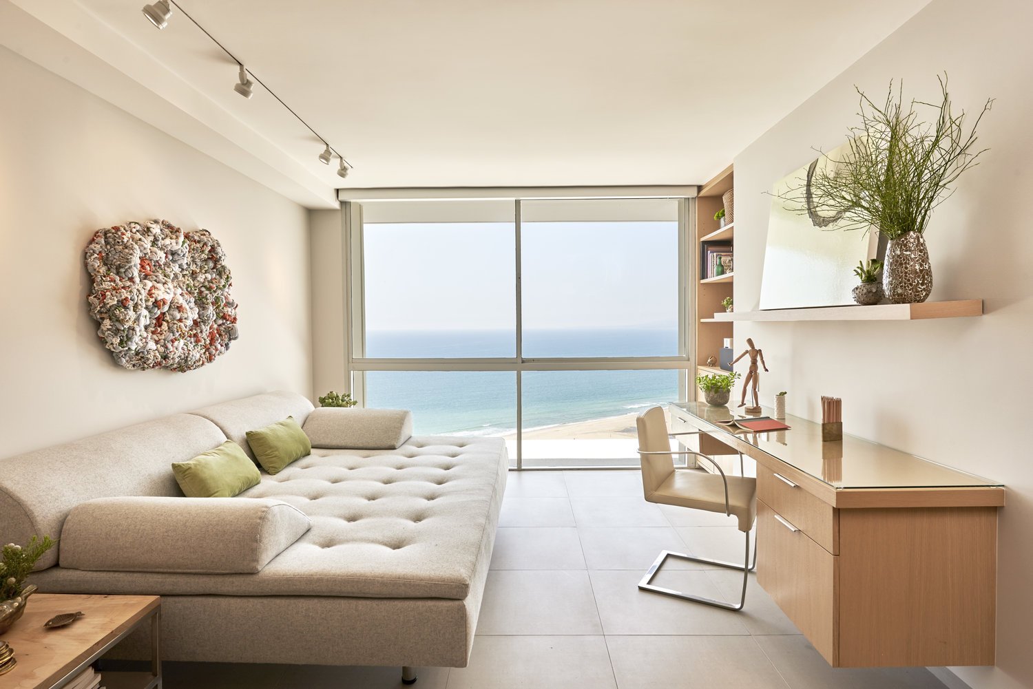 Modern ocean-view living room with a cream sectional sofa and desk. Interior design by Sarah Barnard Design Malibu.
