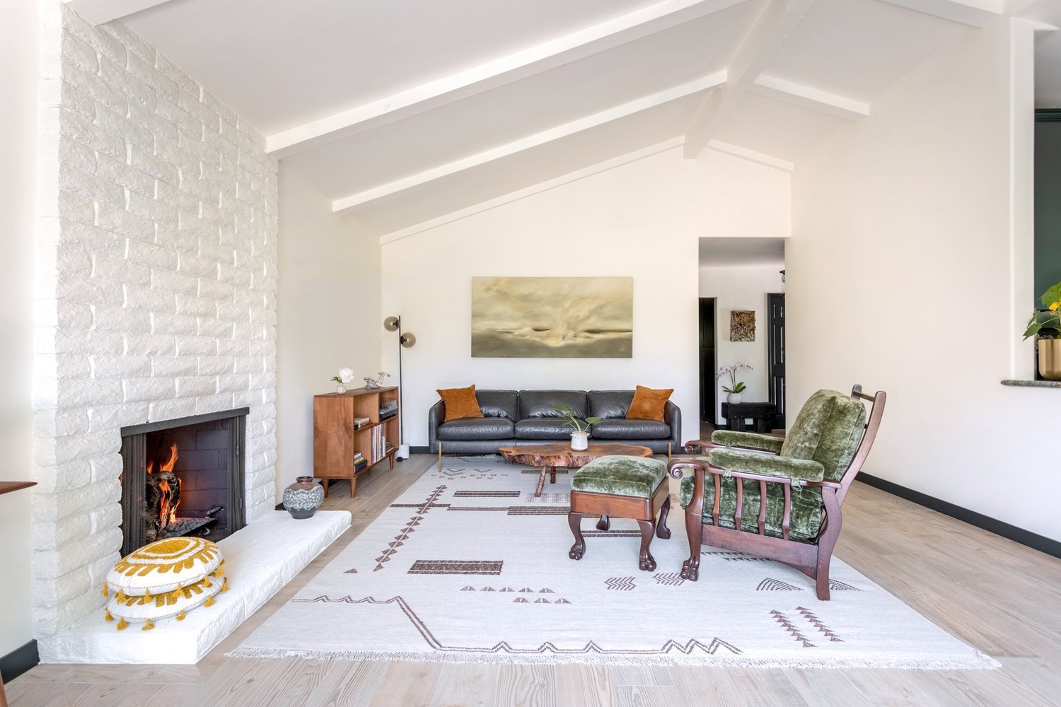 Photo by: Ace Misiunas
A hazy, calming landscape painting by Peter Burega hangs over the living room sofa. The muted earth tones of grey, brown, and olive green resonate with the deep green of the antique velvet armchair.