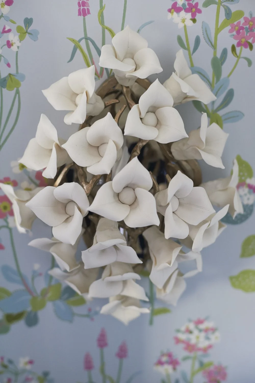 Photo by: Steven Dewall
Handmade porcelain flowers cluster together in this pretty wall sconce. 