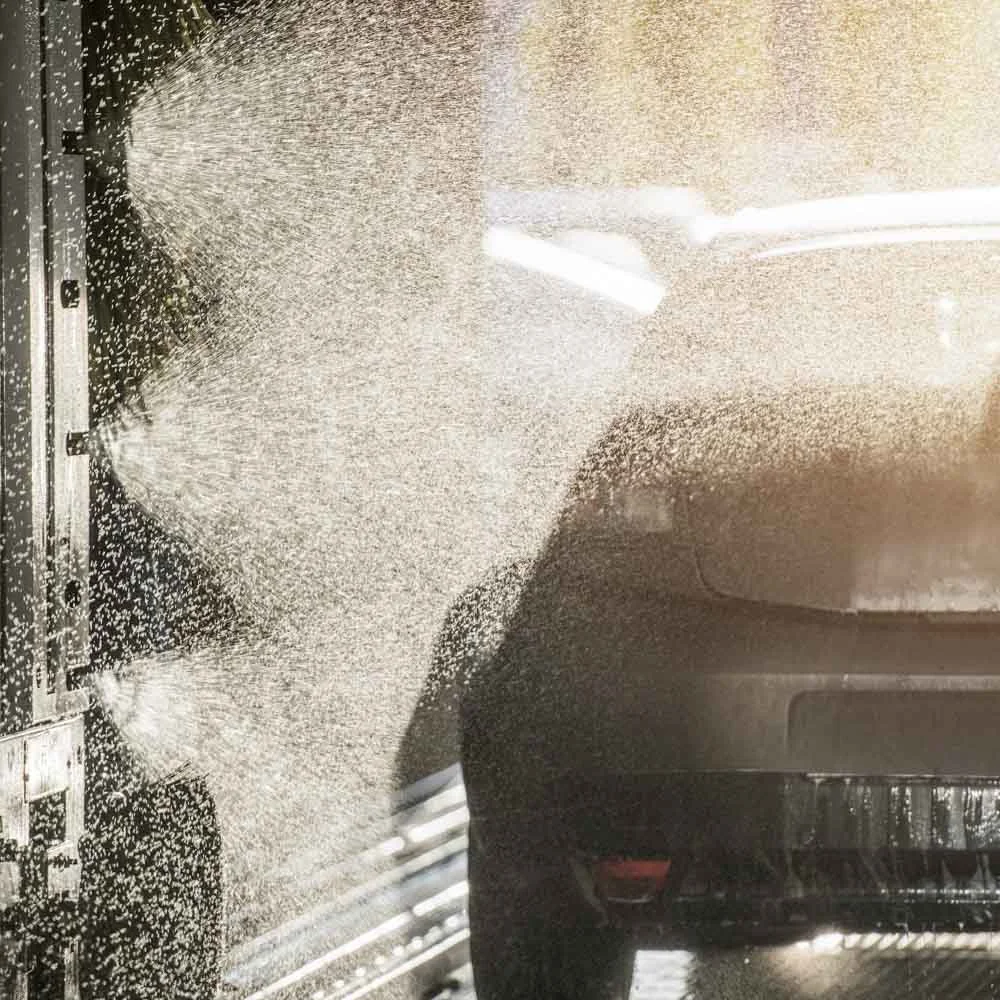 Touchless automatic car wash spraying high-pressure water on commercial vehicle