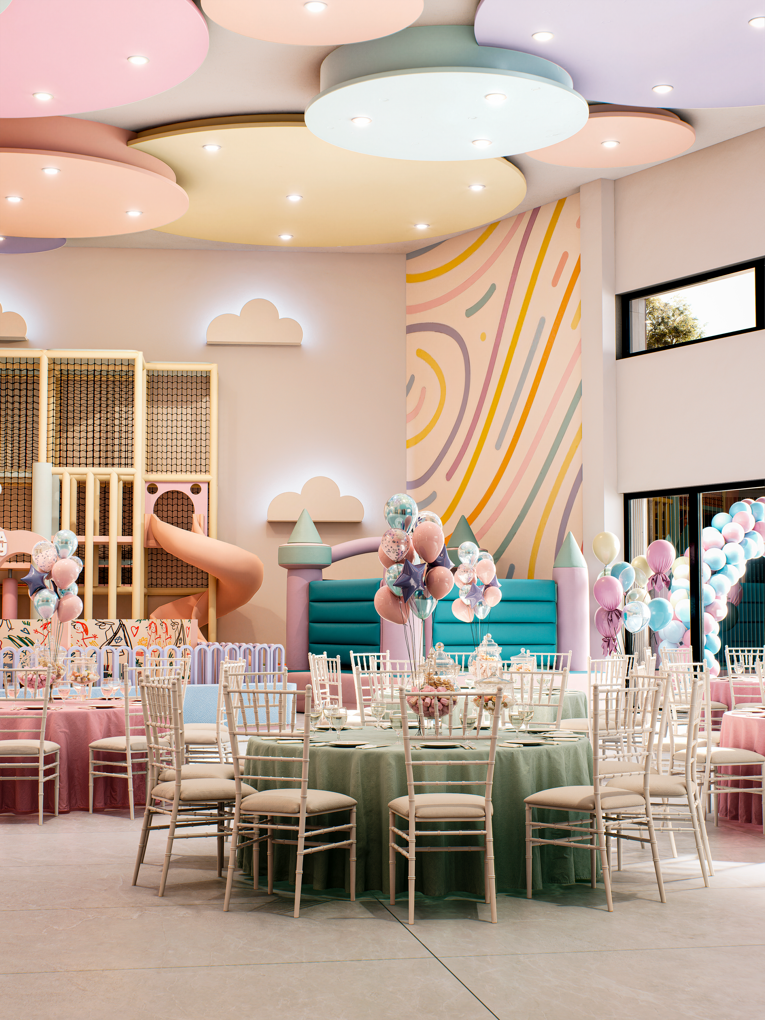 Decoración de fiesta con mesas y sillas blancas, globos de color rosa, azul y morado, y una pared con mural colorido en tonos pastel, en un espacio luminoso y alegre.