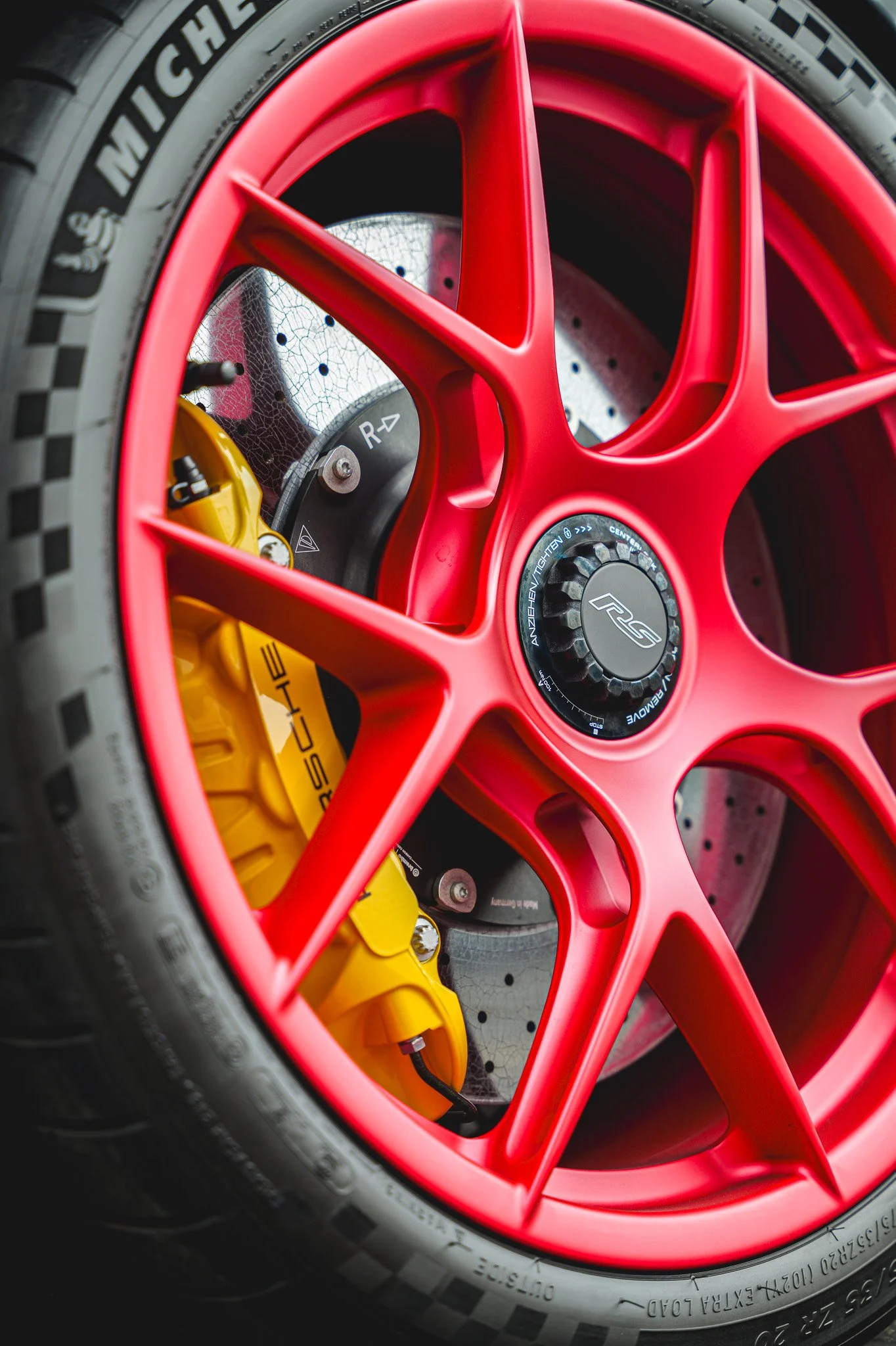 Close-up of a red car wheel with a yellow brake caliper, brake disc, and tire.