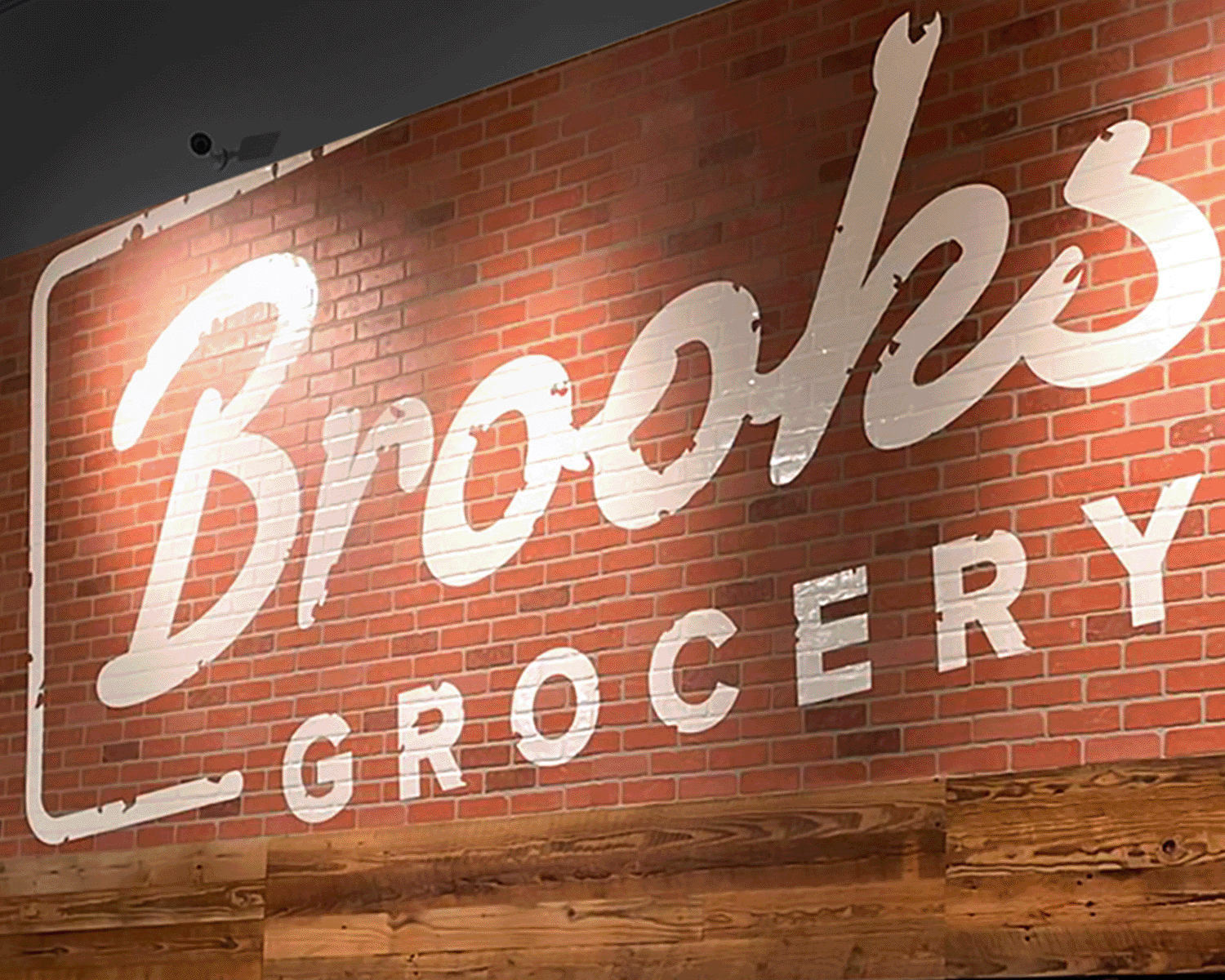 Sign for Broccoli Grocery on a brick wall with wood trim