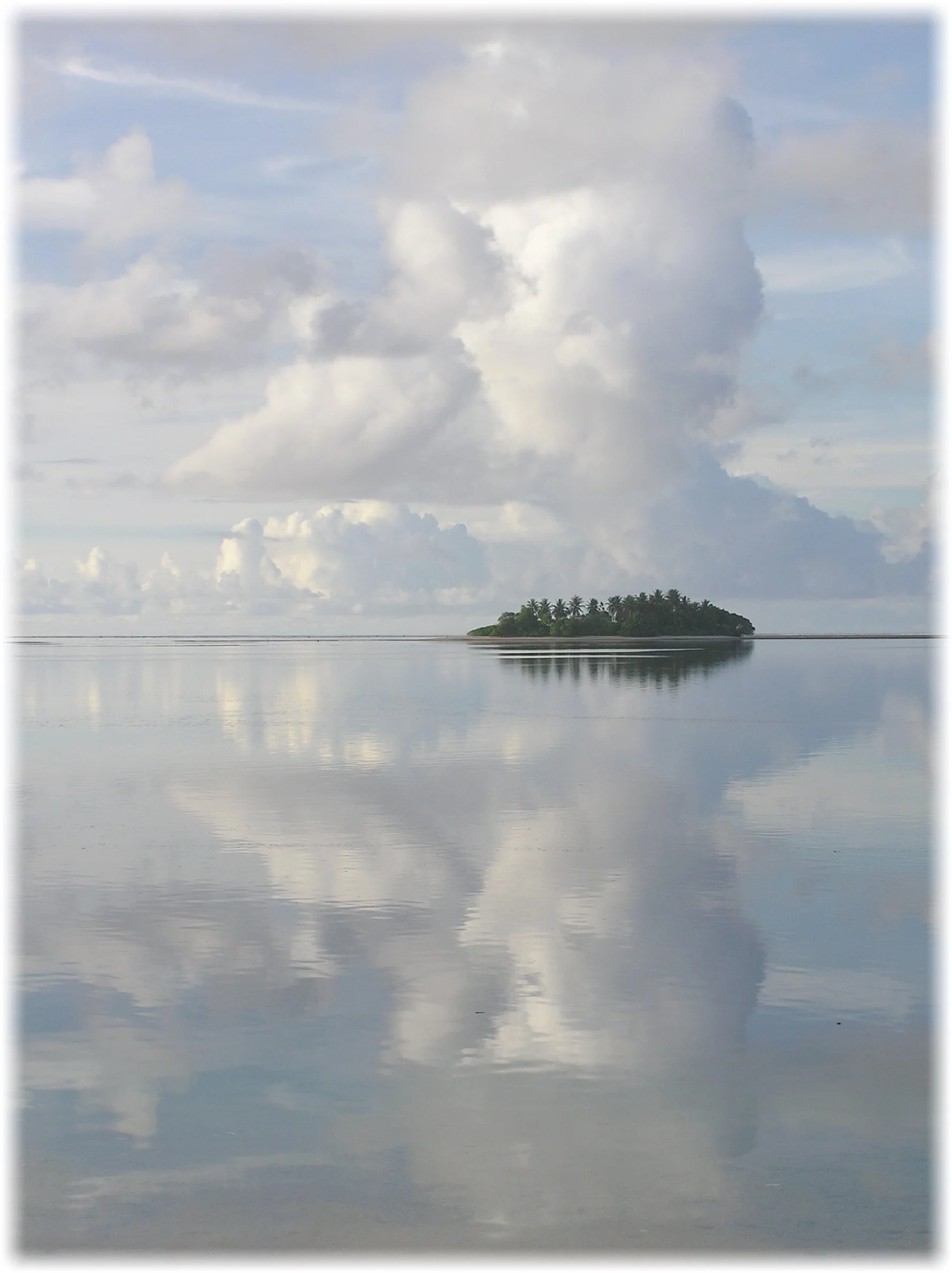 The small islet of Te Afua a Taepoa, Nanumea with ocean and clouds reflecting on the calm water.