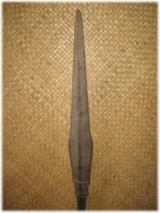 A wooden knitting needle placed on a textured goldish-brown background.