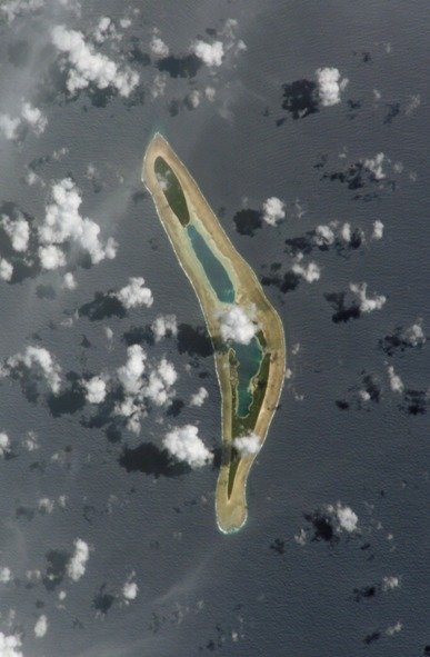 Satellite view of an Nanumea island surrounded by water and scattered clouds.