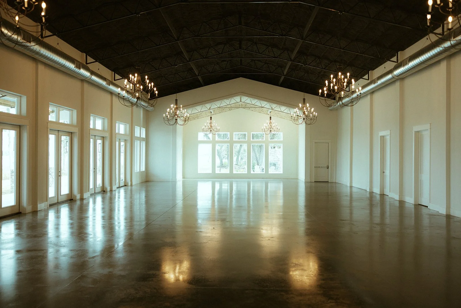 Willow Point Venue's empty ballroom with tall windows and chandeliers