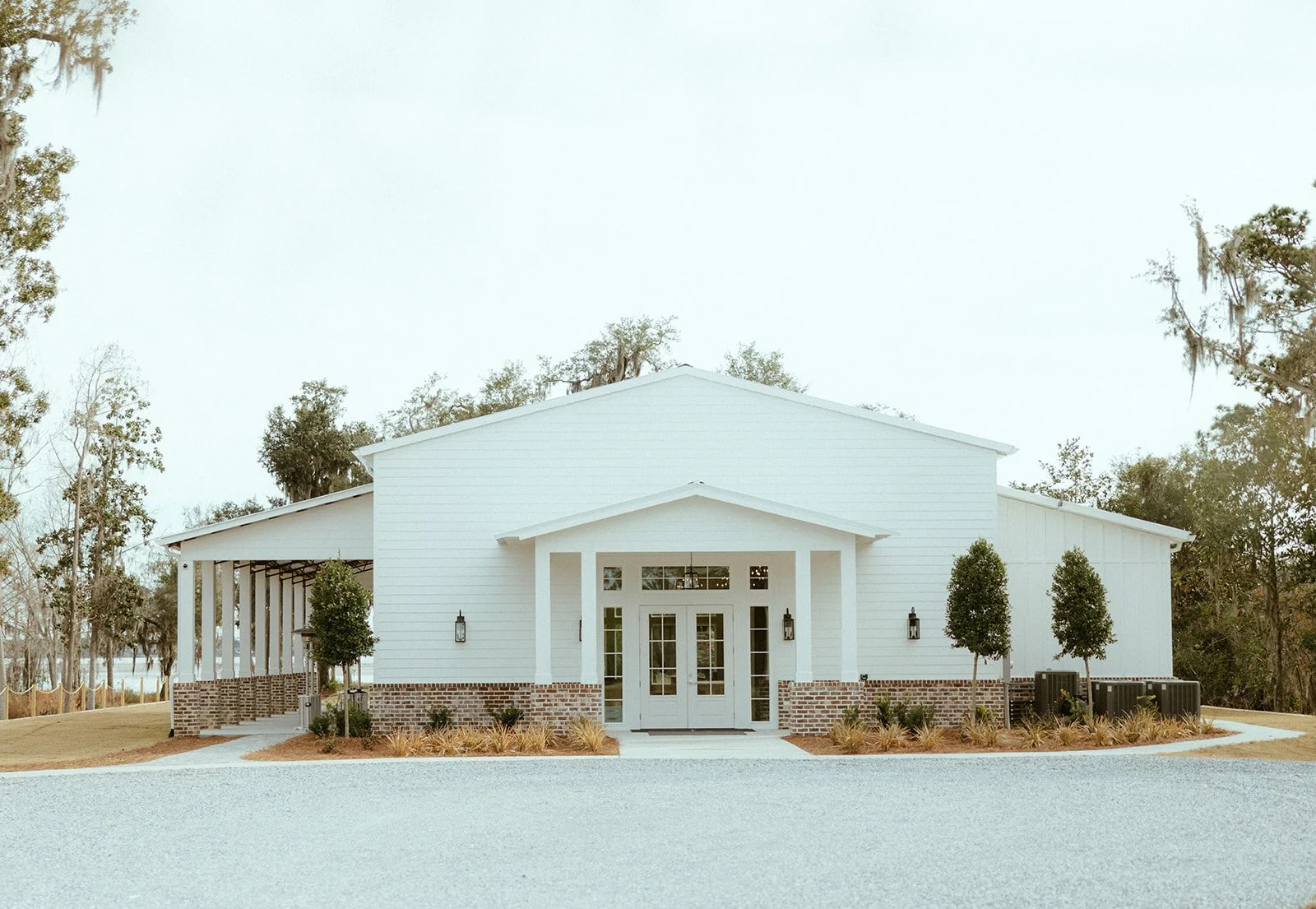 Willow Point Venue's white modern building with brick accents, surrounded by trees and greenery.