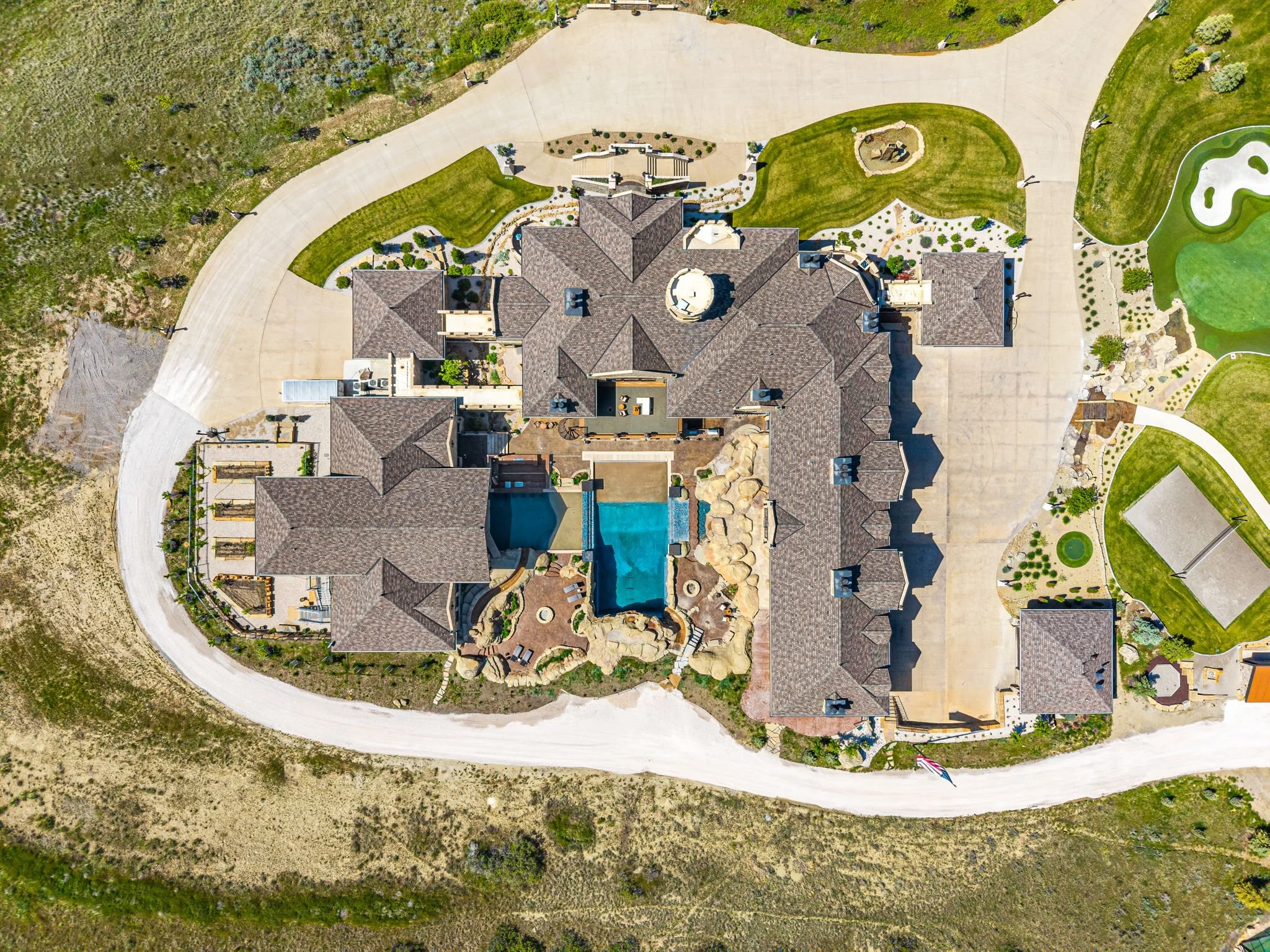 Aerial view of a large house with a swimming pool, surrounded by landscaping, pathways, and outdoor amenities.