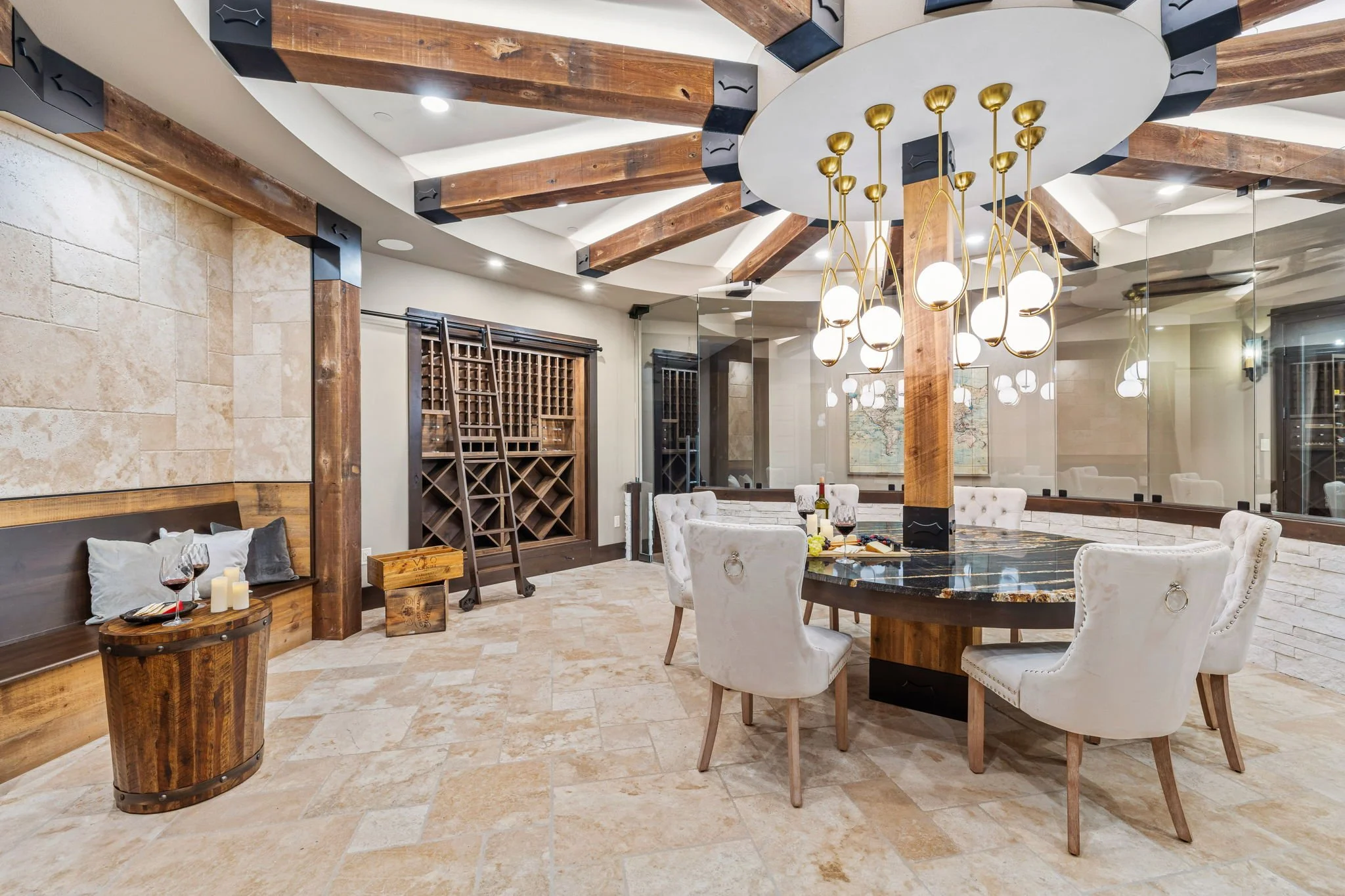 Elegant dining room with a round marble table, white upholstered chairs, and a modern chandelier. Features wood beams on the ceiling and wine storage cabinets.