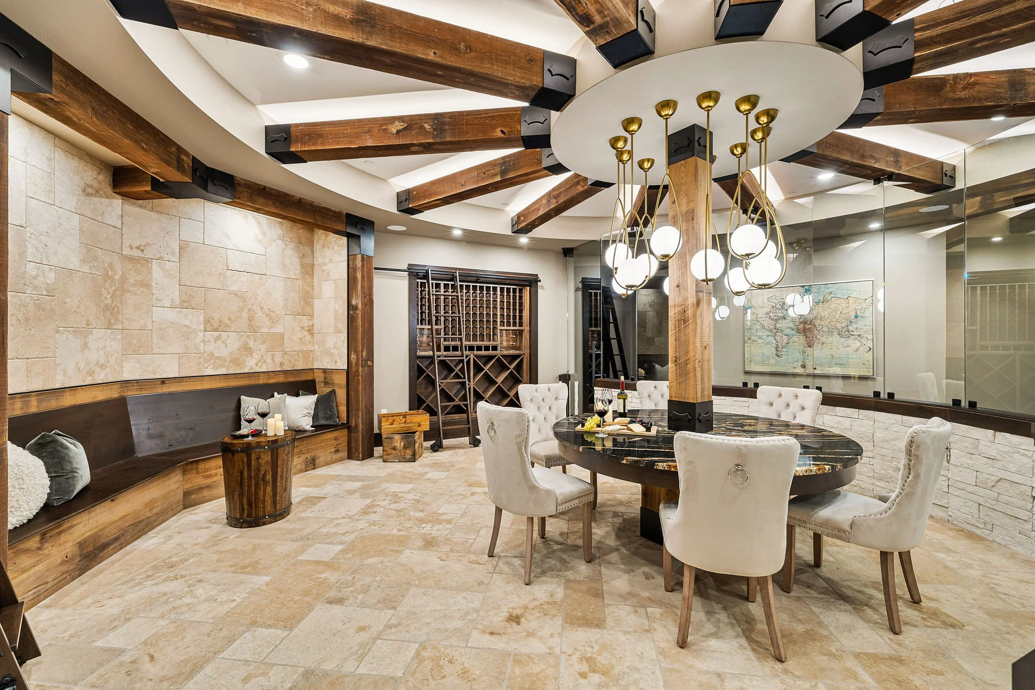 A stylish dining room with a round marble table surrounded by white upholstered chairs, a modern chandelier hanging from a circular ceiling with wooden beams, a wine rack in the background, and a world map on the wall.