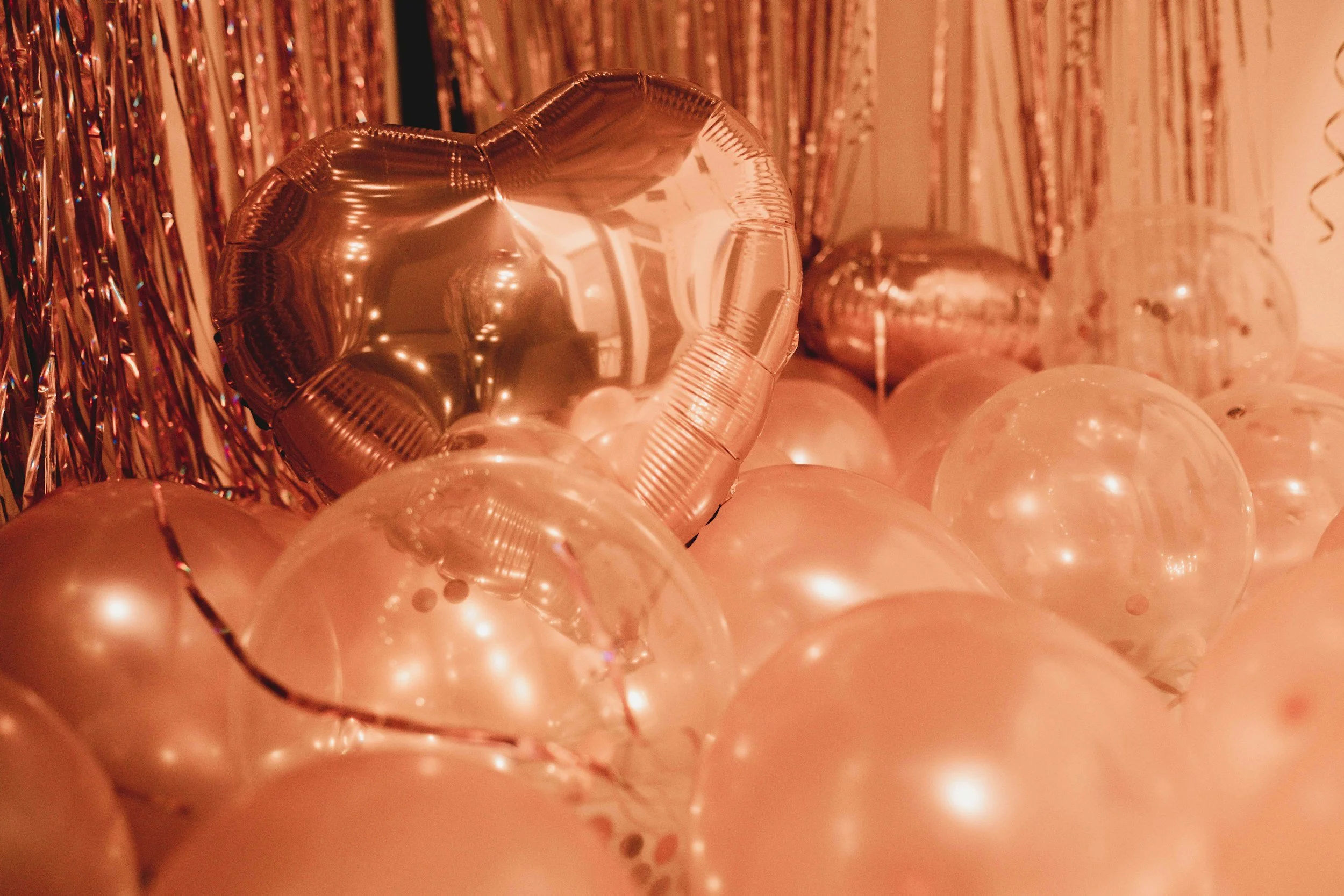 Rose gold balloons and metallic streamers at a party.